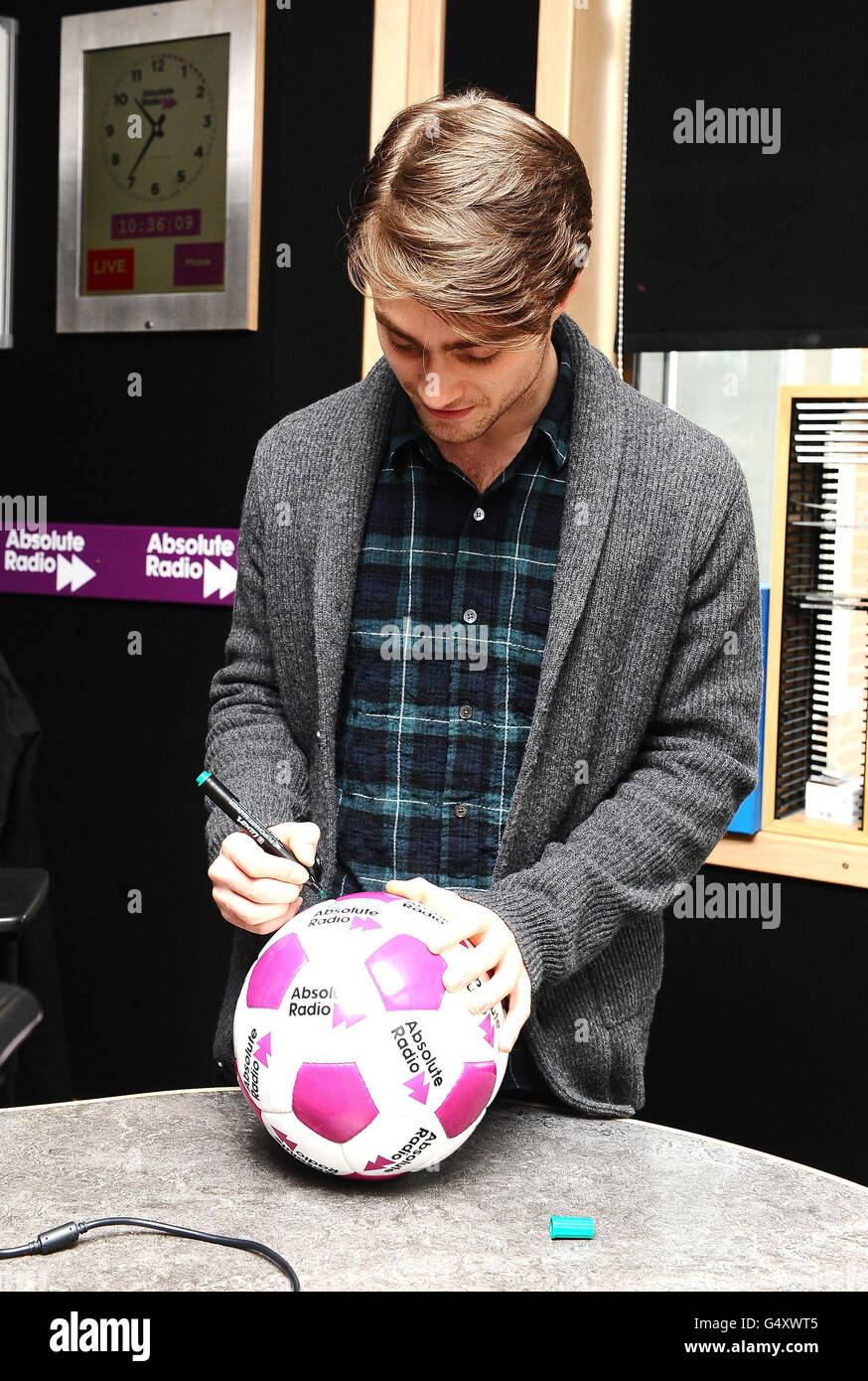 Daniel Radcliffe at Absolute Radio - London. Daniel Radcliffe signs a  football after recording the Dave Gorman Show on Absolute Radio in London  Stock Photo - Alamy