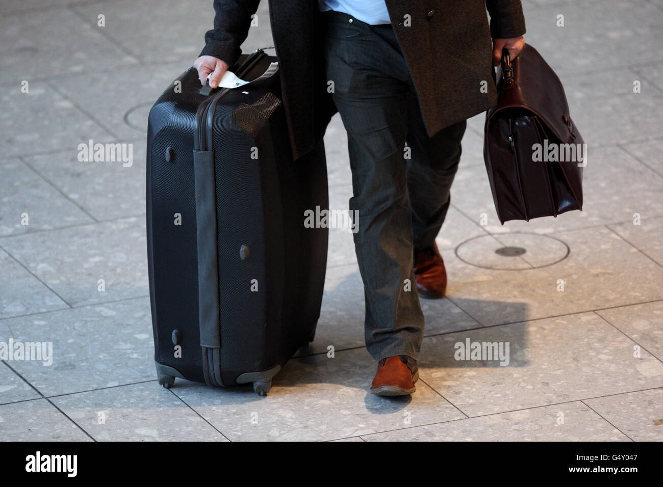 A passenger pushes his bags through terminal 5 of Heathrow Airport Stock Photo