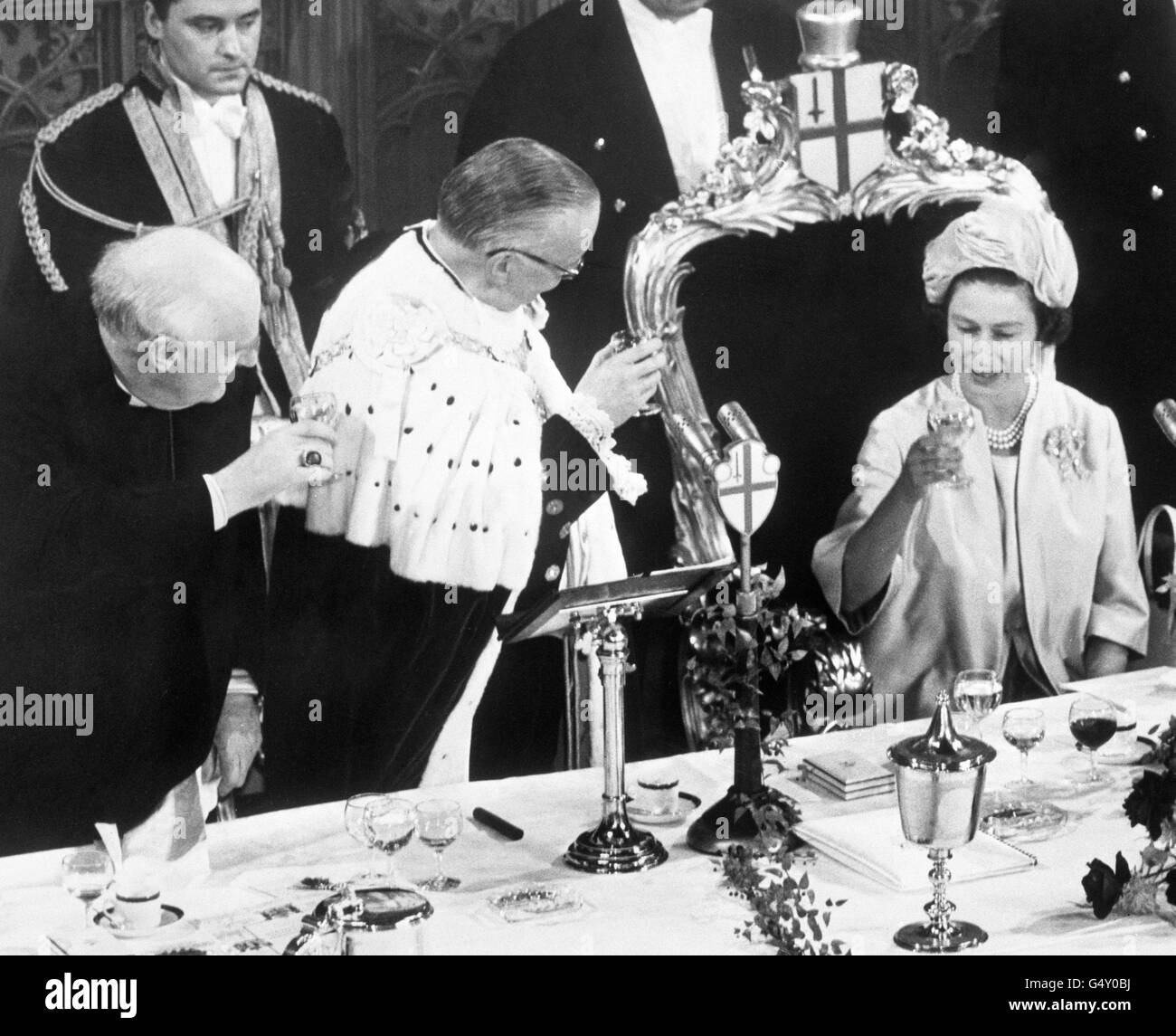 Queen Elizabeth II is toasted by the Archbishop of Canterbury, Dr Michael Ramsey, left, and the Lord Mayor of London, Sir Ralph Perring, at a luncheon given by the Lord Mayor and City Corporation in the Guildhall, London to welcome the Queen and Duke of Edinburgh home from their tour of Australasia. Stock Photo