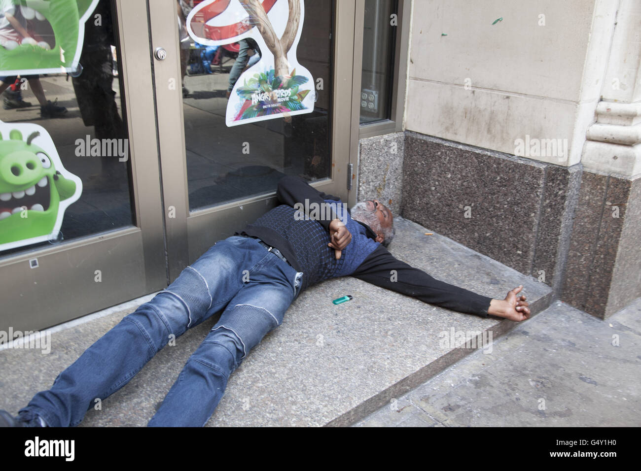 Man passed out on the sidewalk in midtown Manhattan from too much alcohol. Stock Photo