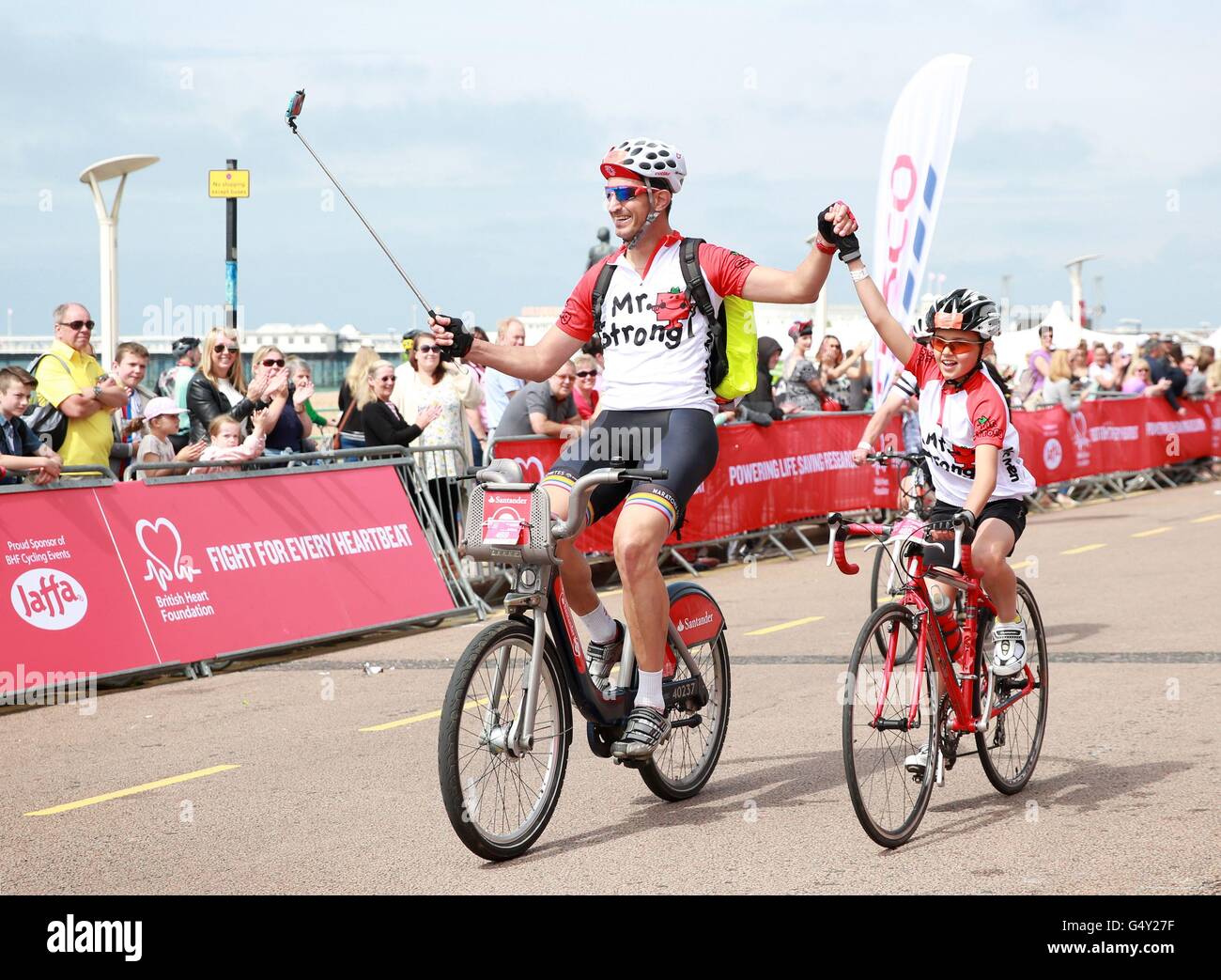 EDITORIAL USE ONLY Father and son Andrew and Xavi Vitalism, 14, cross the finishing line in Brighton, after taking part in the British Heart Foundation's 41st London to Brighton Bike Ride, supported by Tesco and Jaffa. Stock Photo
