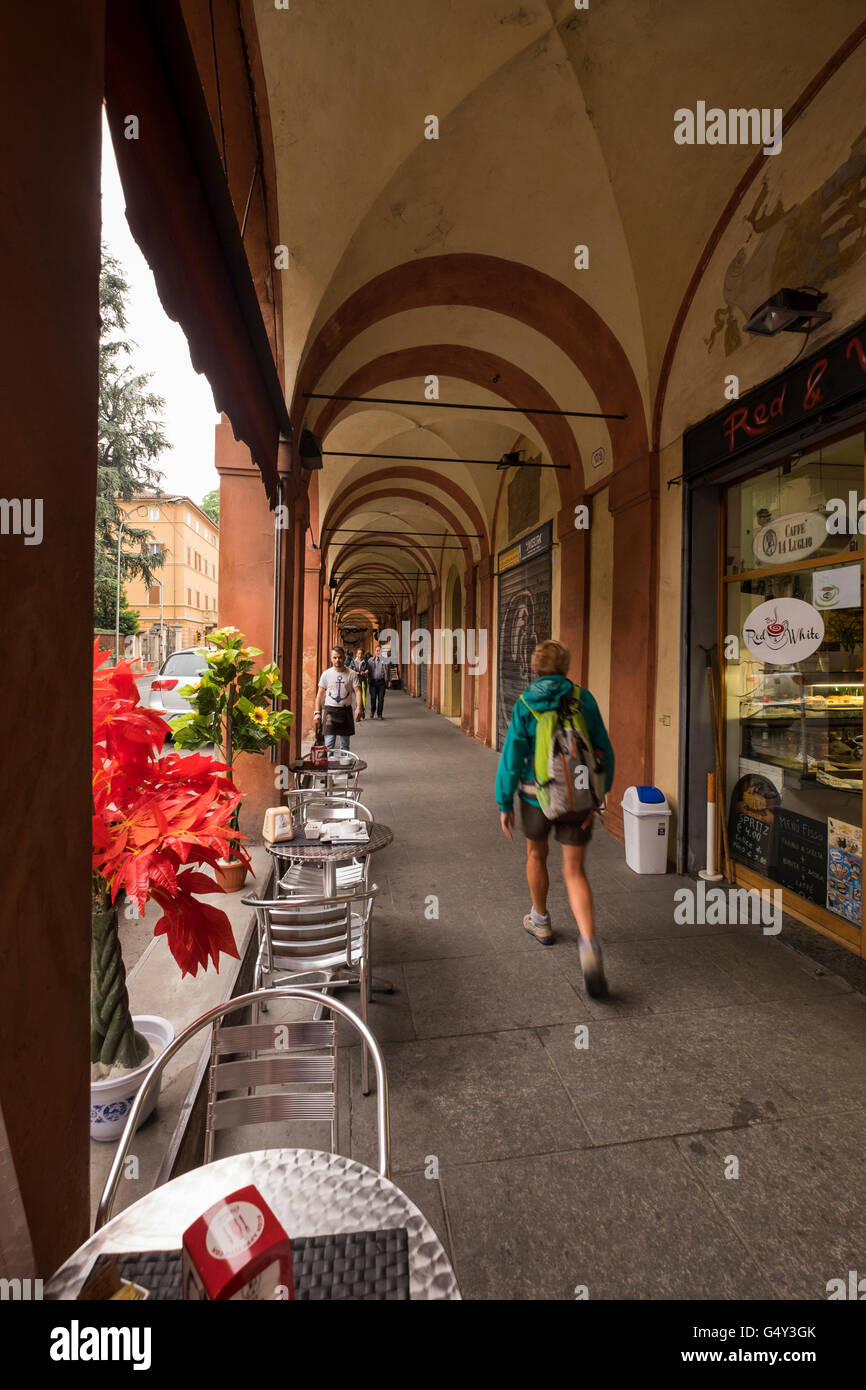 Woman with backpack walking through the porticos on the Via Saragozza, on the way out of Boligna, Italy. Stock Photo