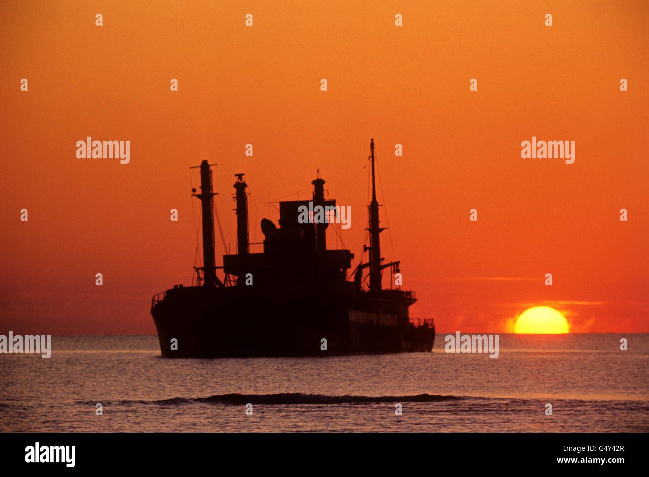 The sun slips below the Mediterranean Sea and silhouettes the SS Dimitrious, grounded near Akritiri, Cyprus, after being on fire. Her crew were rescued by RAF helicopter Stock Photo