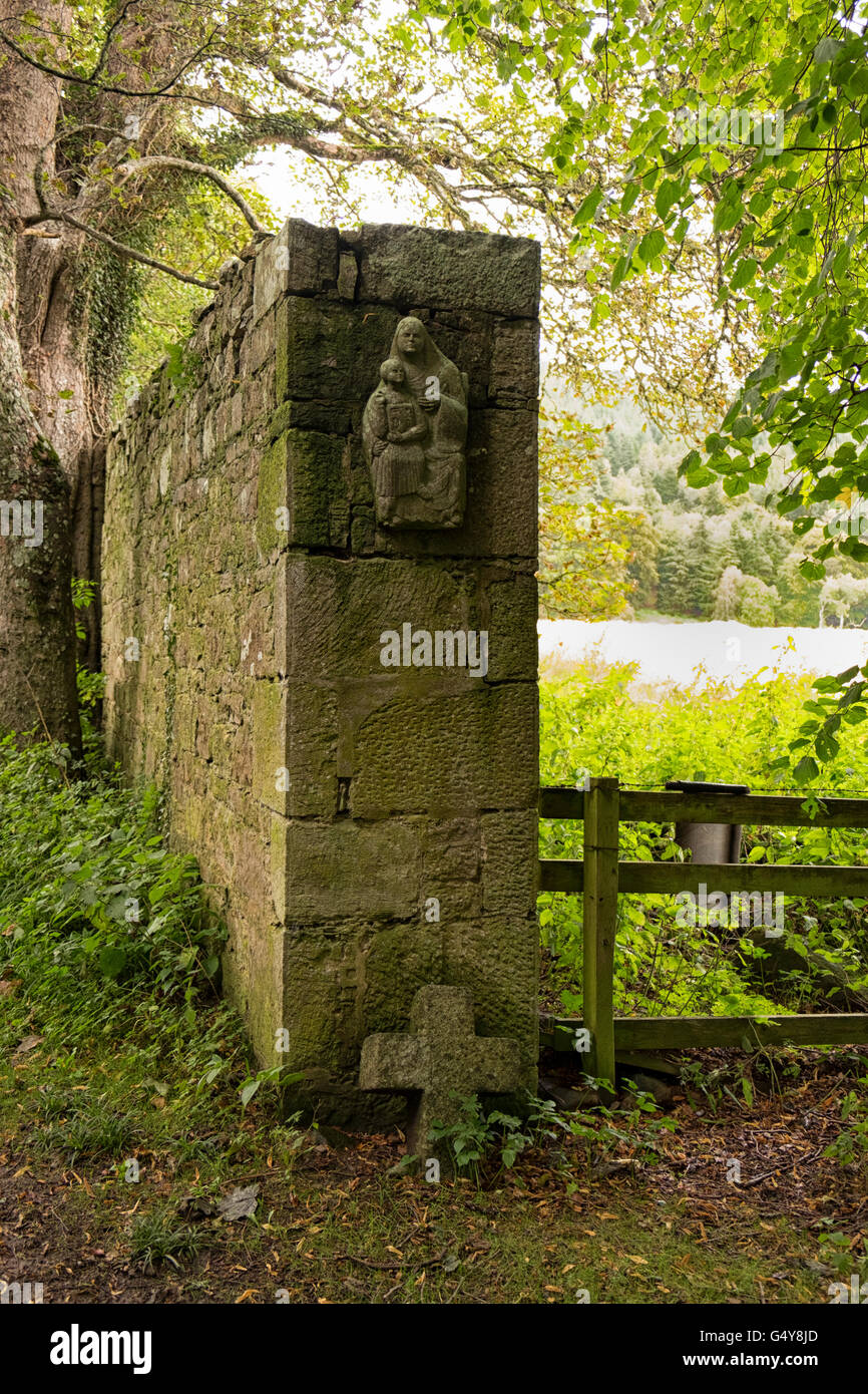 Ancient lichen covered stone wall with religious symbols Stock Photo