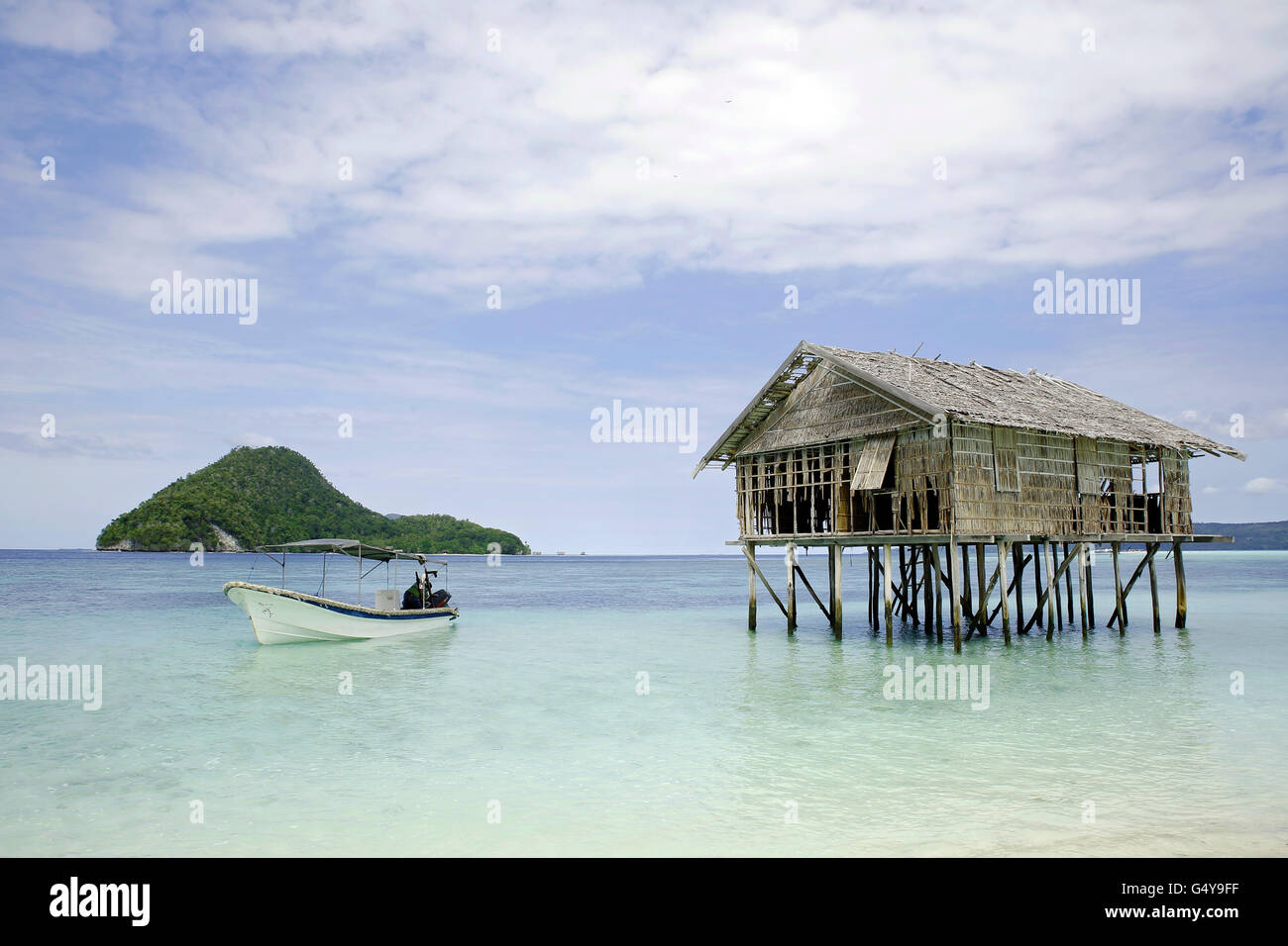 Dive Boat and Water Hut, with View of Kri Island and Dampier Strait. Raja Ampat, Indonesia Stock Photo