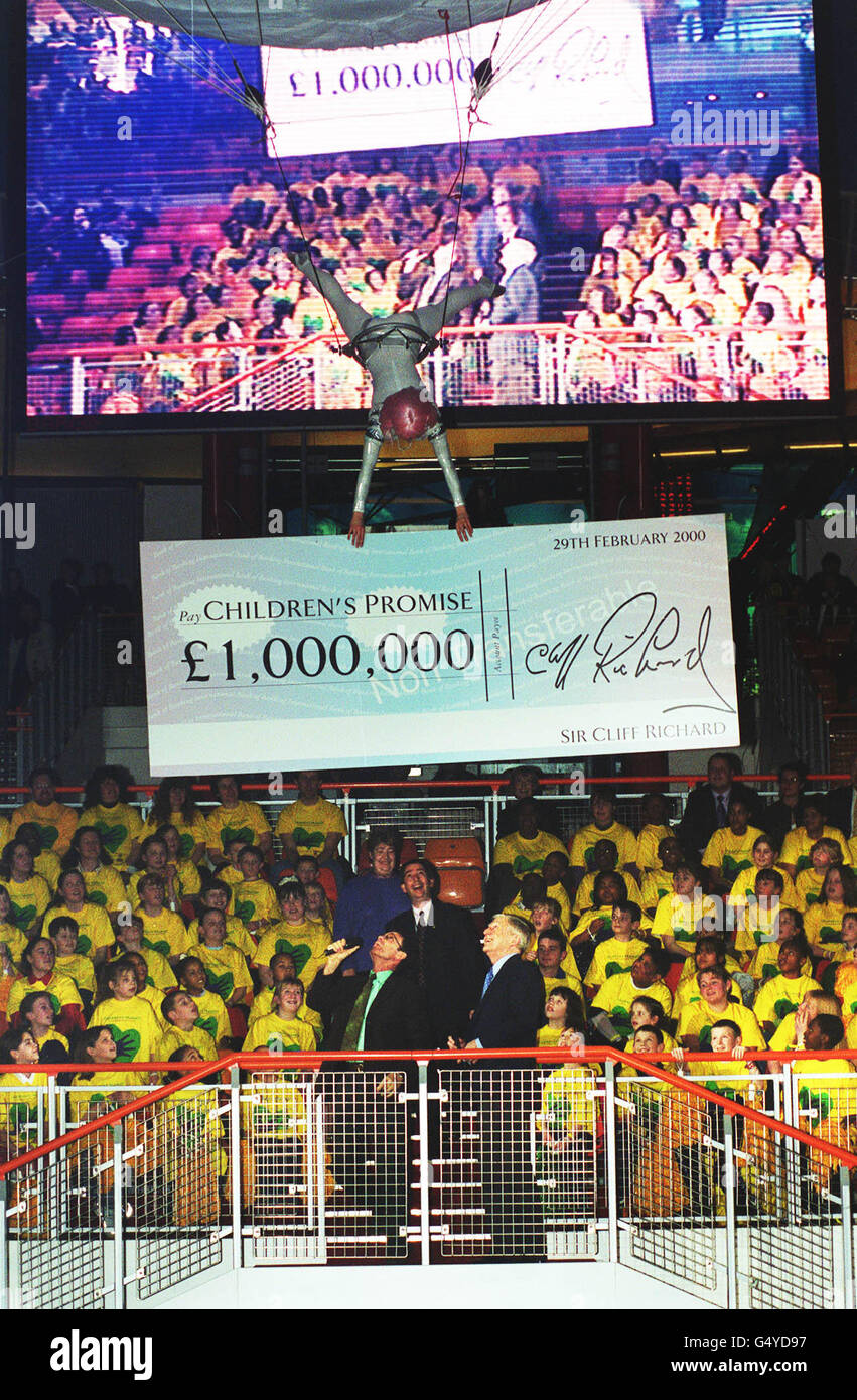 Pop legend Cliff Richard supported by Michael Parkinson presents a personally-signed cheque for 1 million, at the Millennium Dome, south London, as he revealed that a Millennium children's appeal had so far raised 18.5 million. * Sir Cliff's contribution towards the Children's Promise fund came from sales of his number one hit single, Millennium Prayer, and from his New Year's Eve concert in Birmingham. Stock Photo