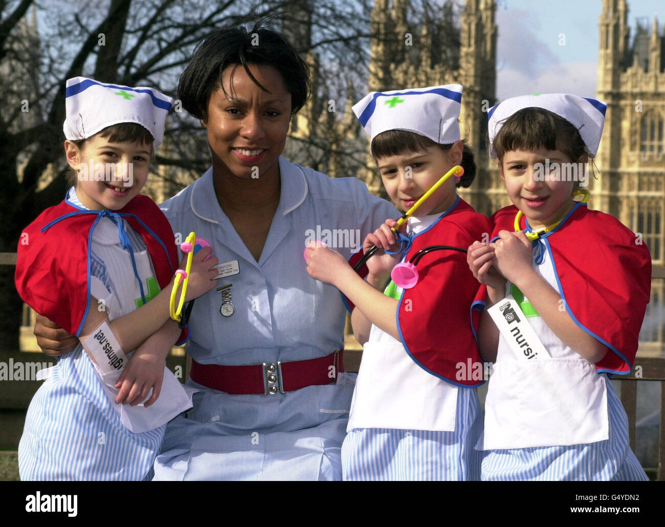 Paediatric Staff Nurse Pat Stanford with 7 year old triplets (L-R) Gabrielle, Alexandra and Eleanor Grant, from St. Albans, outside St Thomas' Hospital, London, where the Government announced a major recruitment drive in the NHS. * The three young girls from St Albans dressed up in nurses uniforms to demonstrate that the nursing profession is not dead. The drive will be accompanied by a high-profile advertising campaign. Stock Photo
