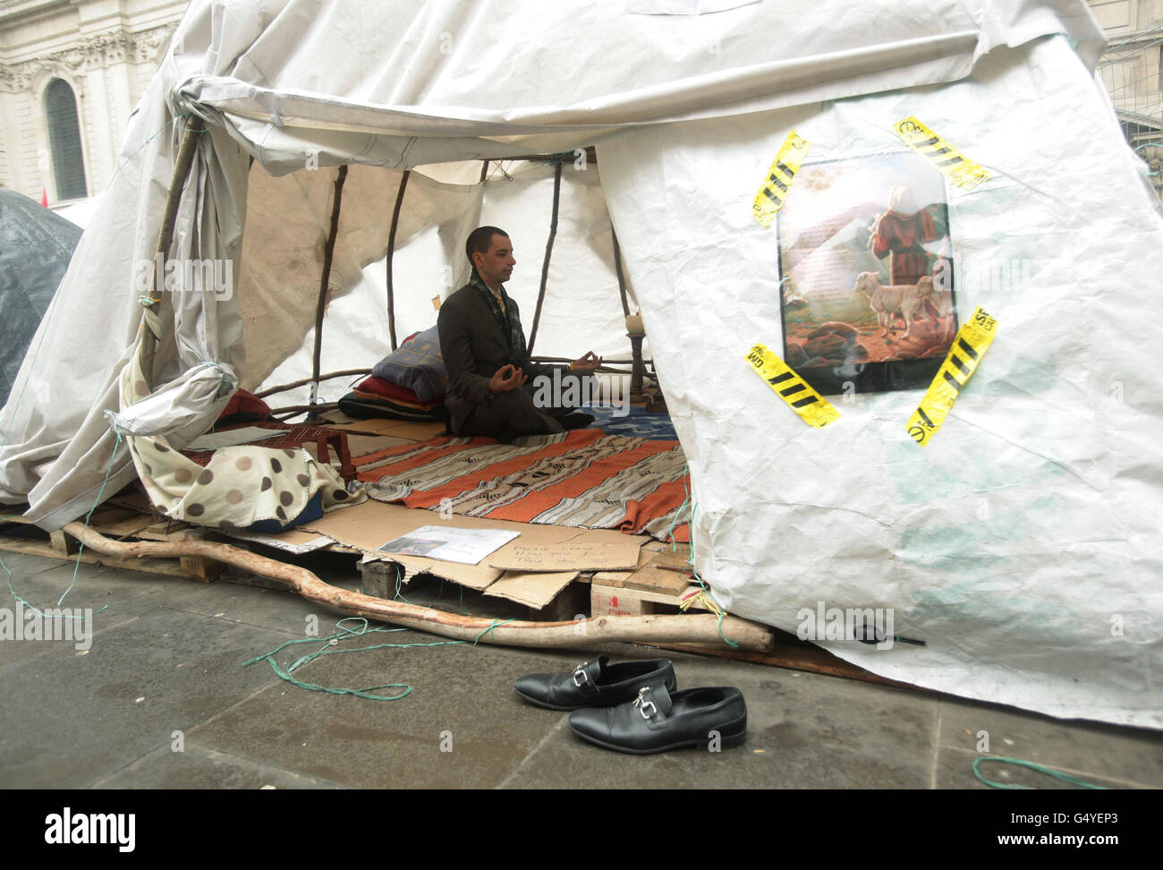 A man meditates inside a tent at the site of Occupy outside St Paul's Cathedral in the City of London. The legal steps taken to evict the anti-capitalist protesters were more 'extreme and draconian' than necessary, the Court of Appeal heard today. Stock Photo