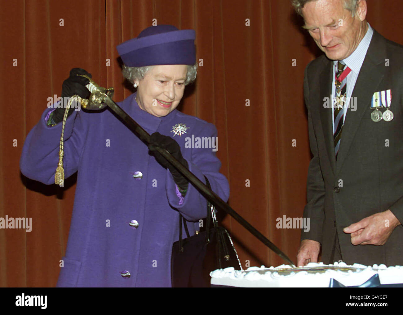 Britains Queen Elizabeth II, cuts a cake with a ceremonial sword