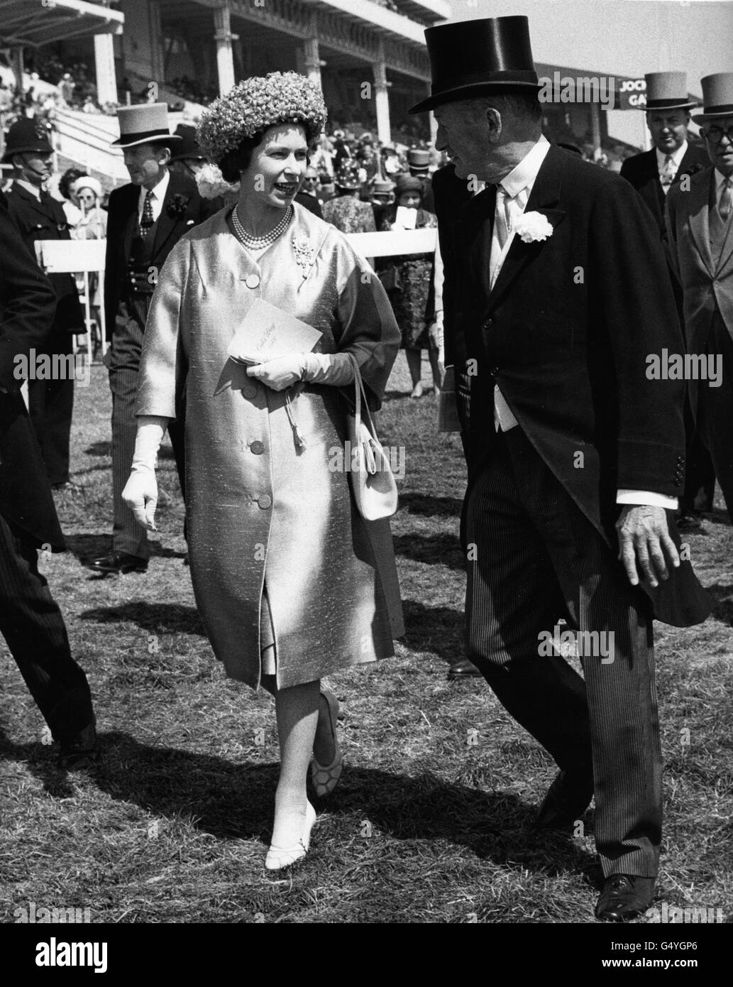 Queen Elizabeth II talks to Sir Humphrey de Trafford, one of the stewards of the meeting, as she walked to the paddock to see her filly 'Arbitrate' saddled for the Oaks. The race was won by Monade, and 'Arbitrate' was unplaced. Stock Photo