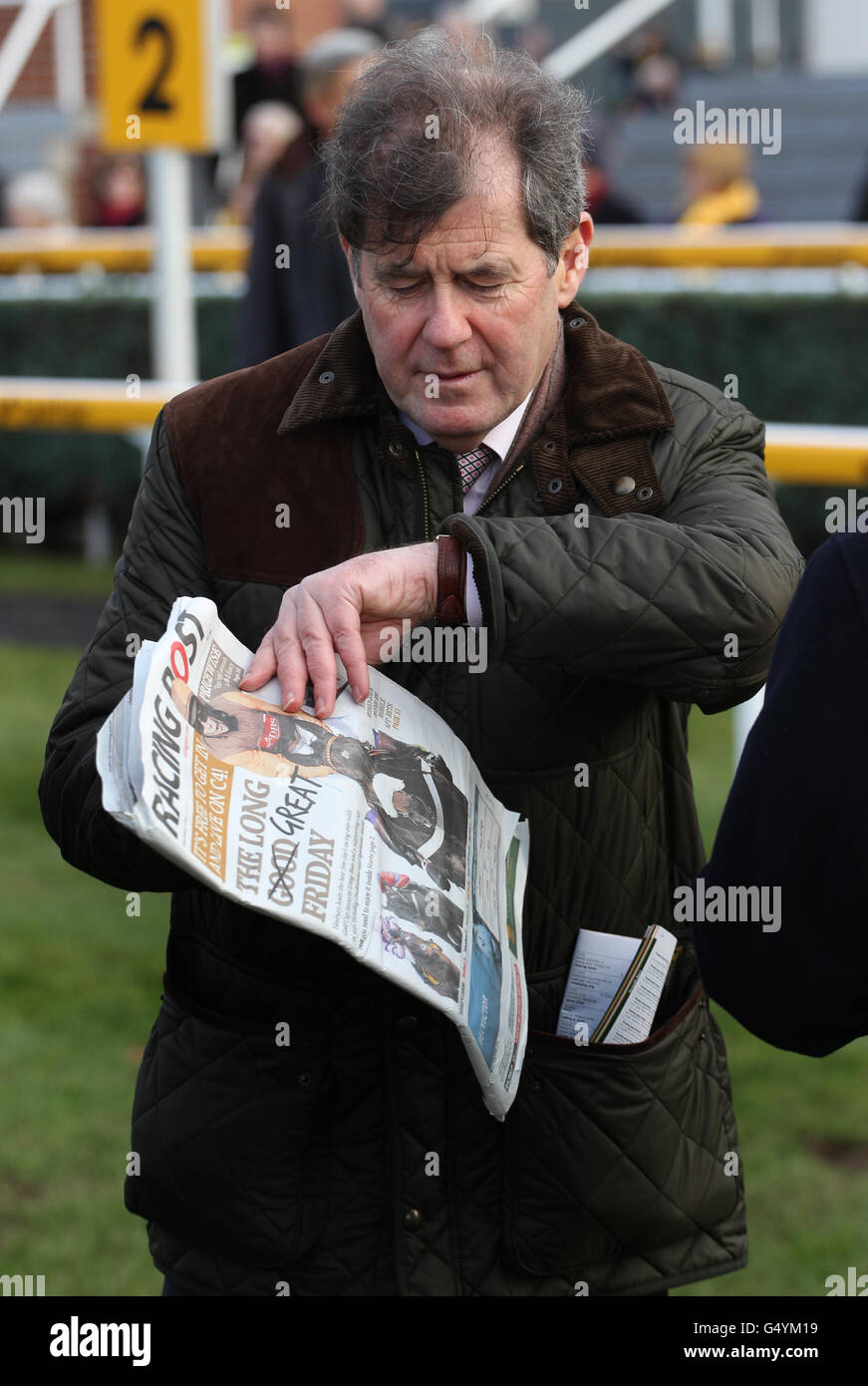 Owner JP McManus read the Racing Post after winning The Betfair Mobile for Best Prices Bumper A Standard Open National Hunt during the Betfair Free Friday at Newbury Racecourse, Newbury. Stock Photo