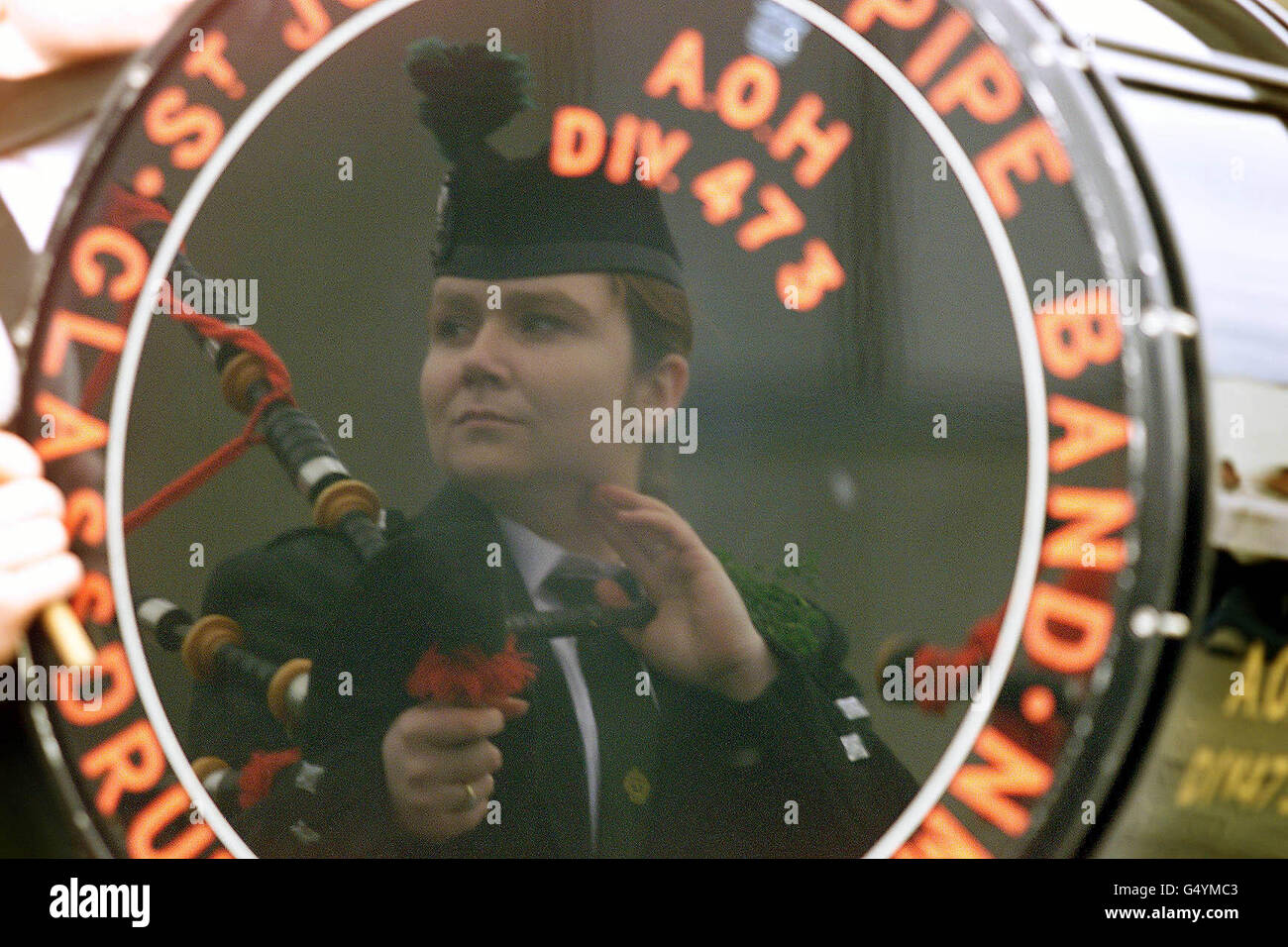 A piper reflected in the drum of St Joseph's AOH flute band, during St
