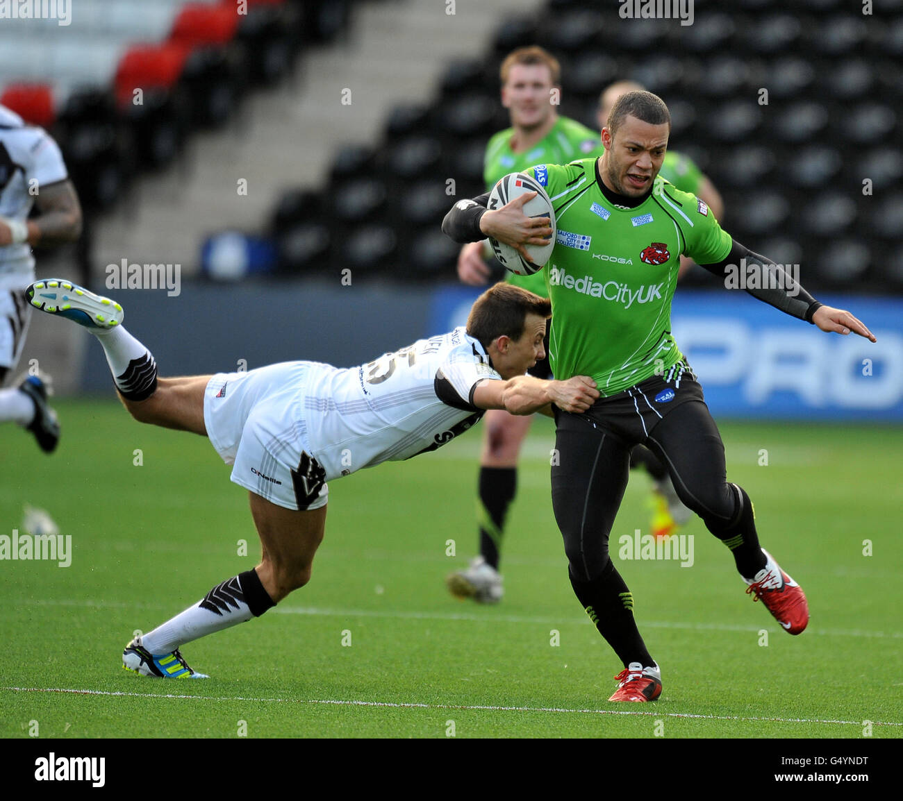 Widnes Vikings' Danny Craven holds on to Salford City Reds' Danny Williams who is dressed to avoid possible burns on the Widness pitch Stock Photo