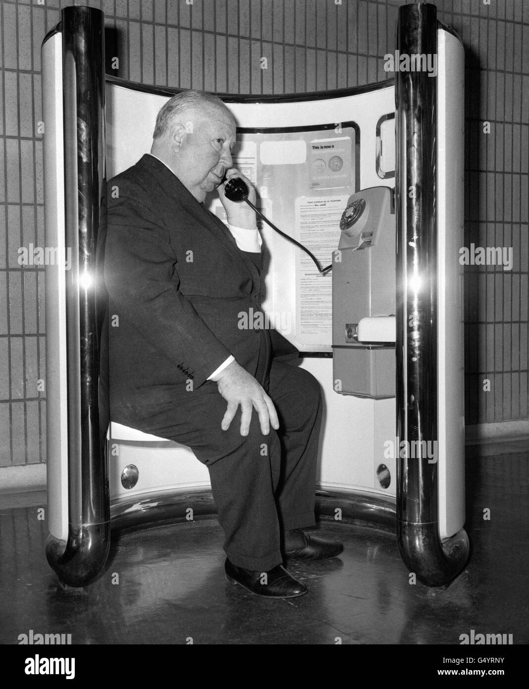 Film director Alfred Hitchcock makes a telephone call at Heathrow Airport, before flying to Los Angeles, after making his film 'Frenzy'. Stock Photo