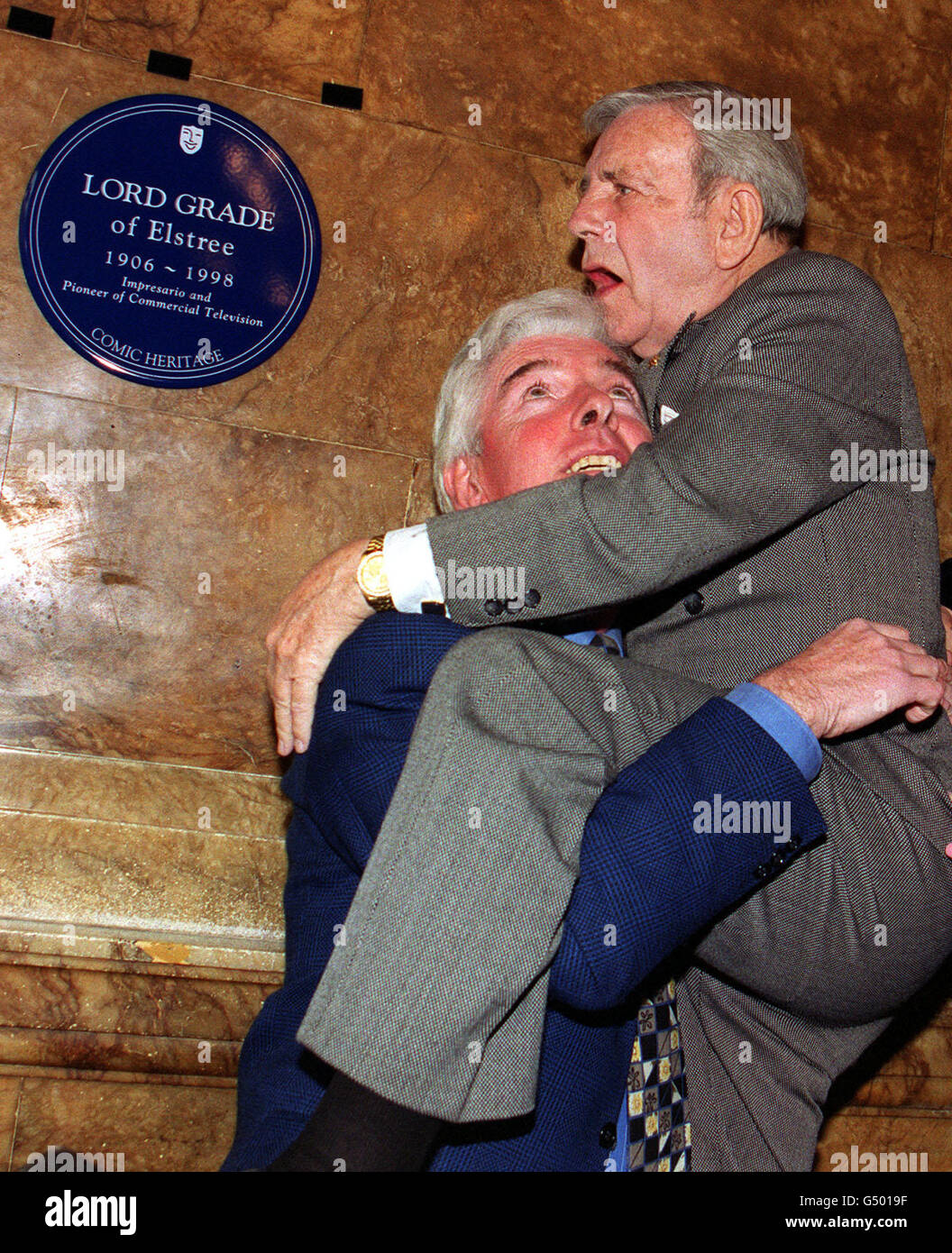 Comedian Sir Norman Wisdom uses fellow comedian Tom O'Connor to get a better view of a blue plaque unveiled in honour of Lord Grade at the London Palladium. The plaque, from Comic Heritage, was laid in recognition of Lew Grade's unique contribution to British Comedy and entertainment. Stock Photo