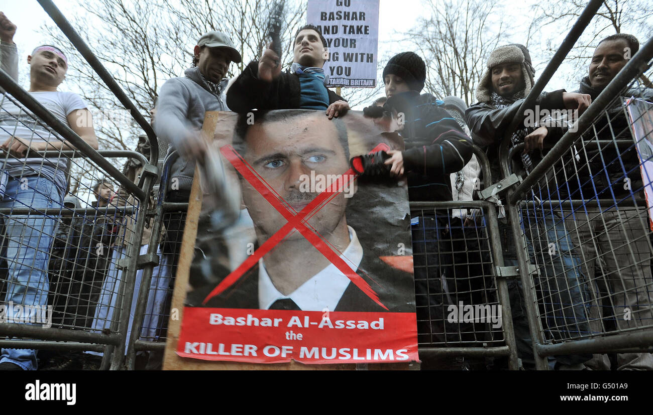 Protesters beat a poster of President Assad with their shoes outside the Syrian Embassy in Belgrave Square in central London, demonstrating about the escalating conflict in Syria. Stock Photo