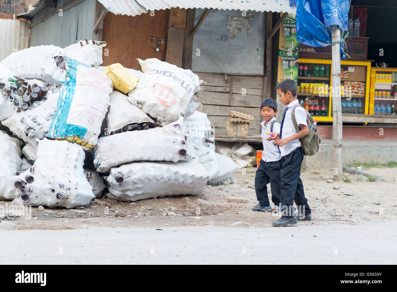 Nepal, Western Region, Besisahar, Annapurna Circuit - Kathmandu to Bhulbhule - pupils on the way home in Besisahar next to sacks of empties bottles Stock Photo
