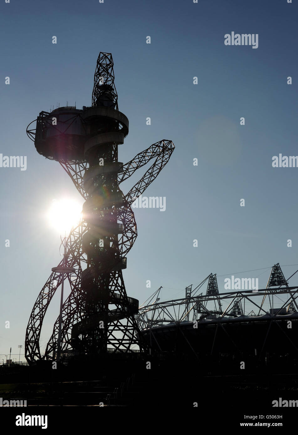 A view of the sun silhouetting Olympic Stadium next to the ArcelorMittal Orbit in the Olympic Park, London. Stock Photo