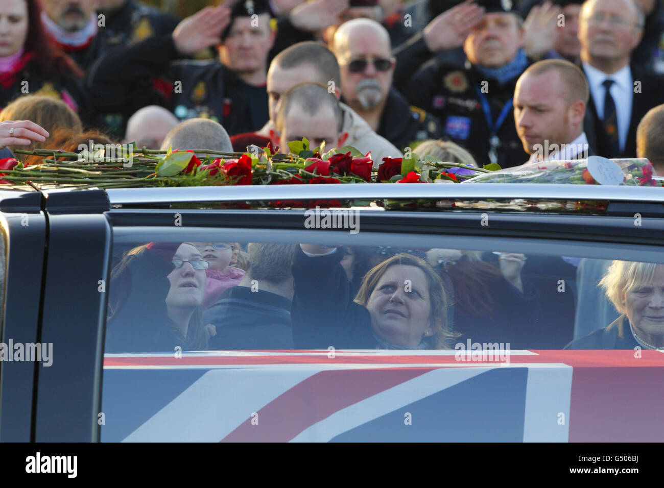 The family of Senior Aircraftman Ryan Tomlin, of 2 Squadron, Royal Air Force Regiment, place flowers on the hearse as his coffin passes the Memorial Garden in Carterton, Oxfordshire following his repatriation to the UK. Stock Photo