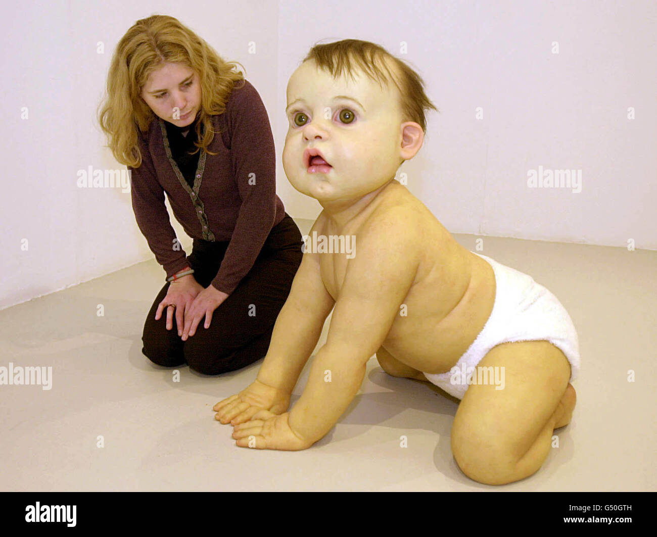 The Saatchi Gallery press officer Philly Adams examines Big Baby by artist Ron Mueck. The work is just one of the displays at the 'Ant Noises' exhibition at the North London gallery, which is open from April 20 to August 20 2000. Stock Photo