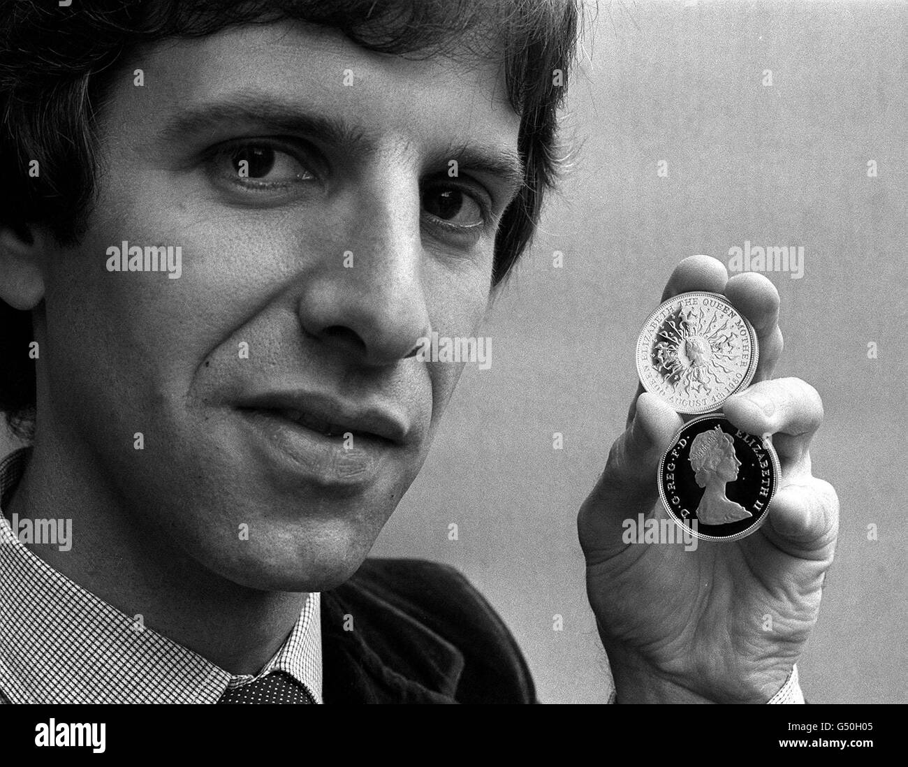 Robert Elderton, who engraved the commemorative 25 pence crown for the Queen Mother's 80th birthday, at the Royal Mint in Llantrisant, South Wales. Elderton is holding two of the coins showing the reverse side (top) the Queen Mother. * ...surrounded by a pattern of bows and lions, based on her family name Bowes-Lyon. Stock Photo