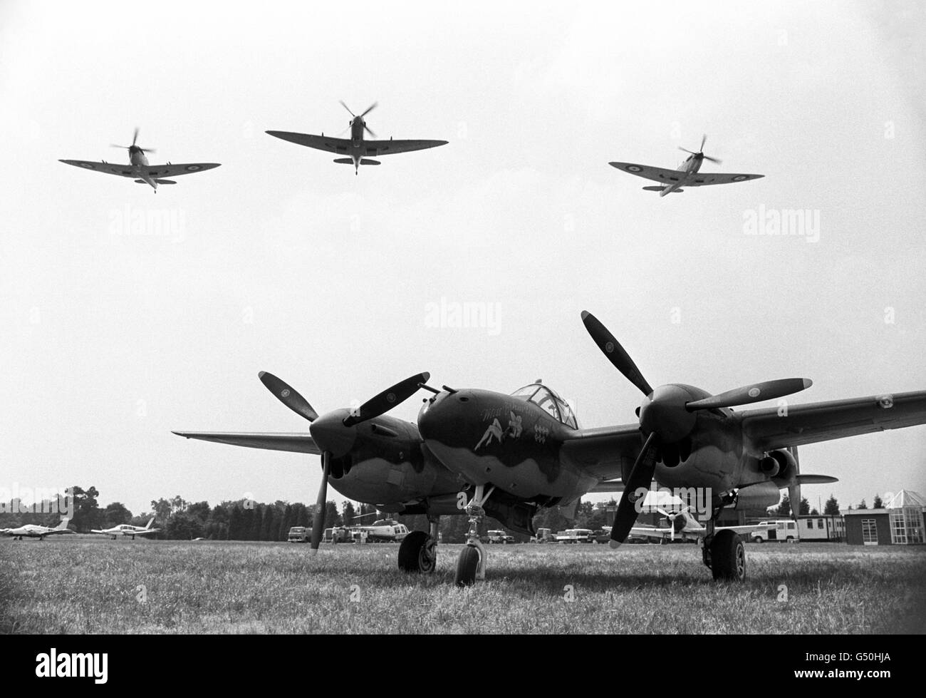 Three Spitfires fly over 'Miss Behaving', a Lockheed P38 Lightning. These vintage aircraft of World War Two are on display at the Biggin Hill International Air Fair Stock Photo