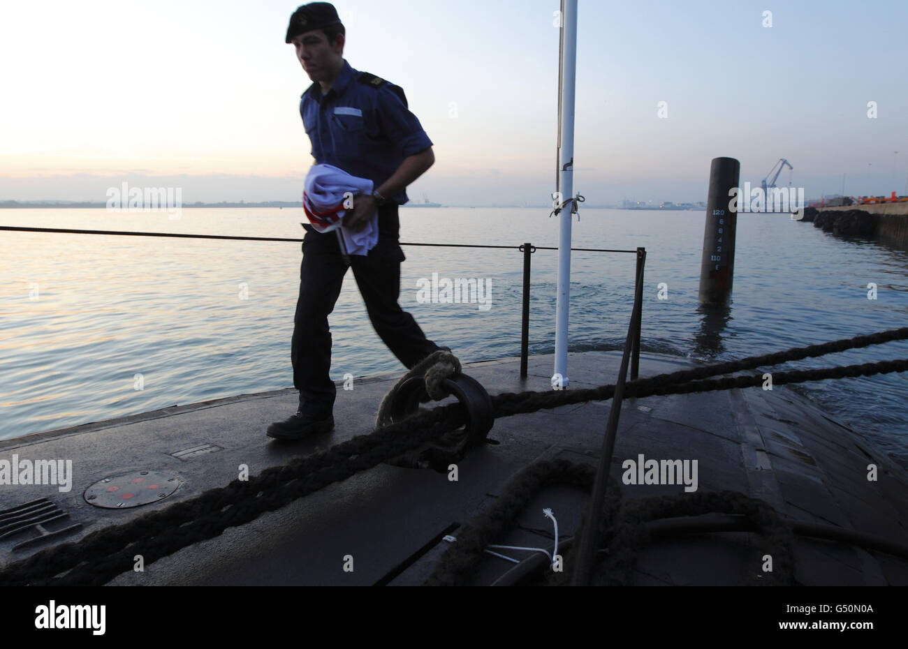 A submariner carries the white ensign below after the evening Colours ceremony aboard the Royal Navy submarine HMS Tireless after arriving in Southampton for a five day visit. Stock Photo