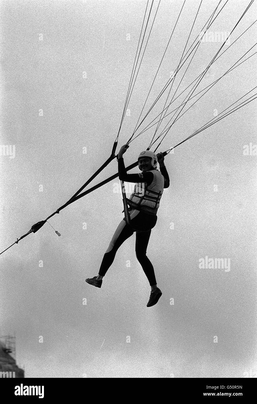 Greater London Council (GLC) leader Ken Livingstone parascending on the River Thames in London, in front of the Houses of Parliament, to promote the council's Thamesday, when a major attraction is to be the Landbeach Parakite Display team. Stock Photo