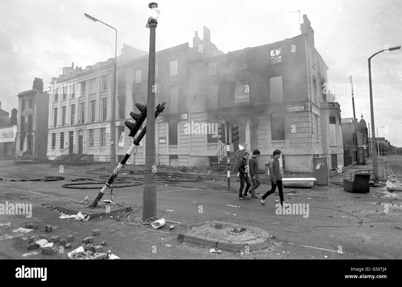 Teenagers survey the aftermath of a second night of violent rioting in the Toxteth district of Liverpool. Stock Photo