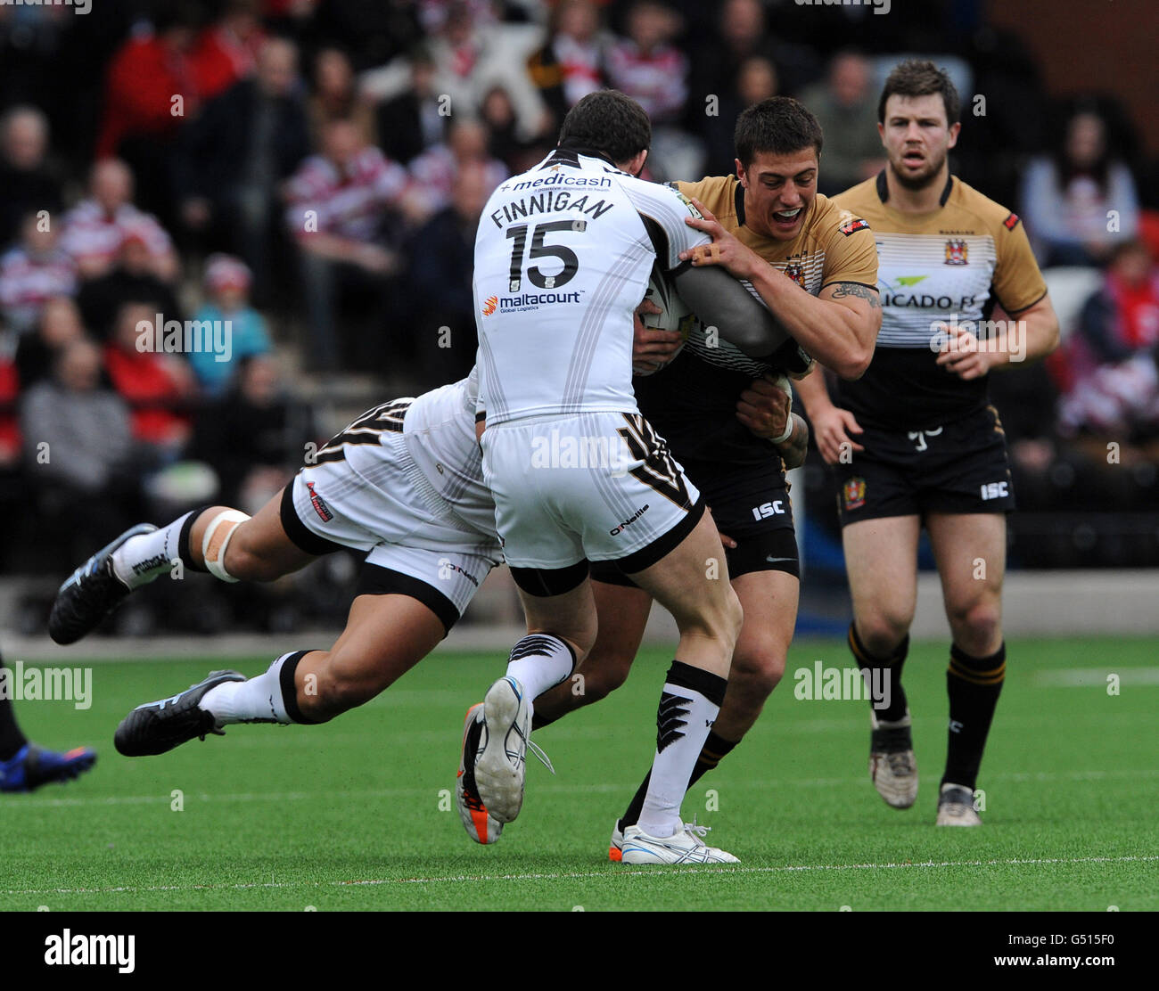 Wigan Warriors' Anthony Gelling is tackled by Widnes Vikings' Simon Finnigan (15) and Frank Winterstein (hidden). Stock Photo