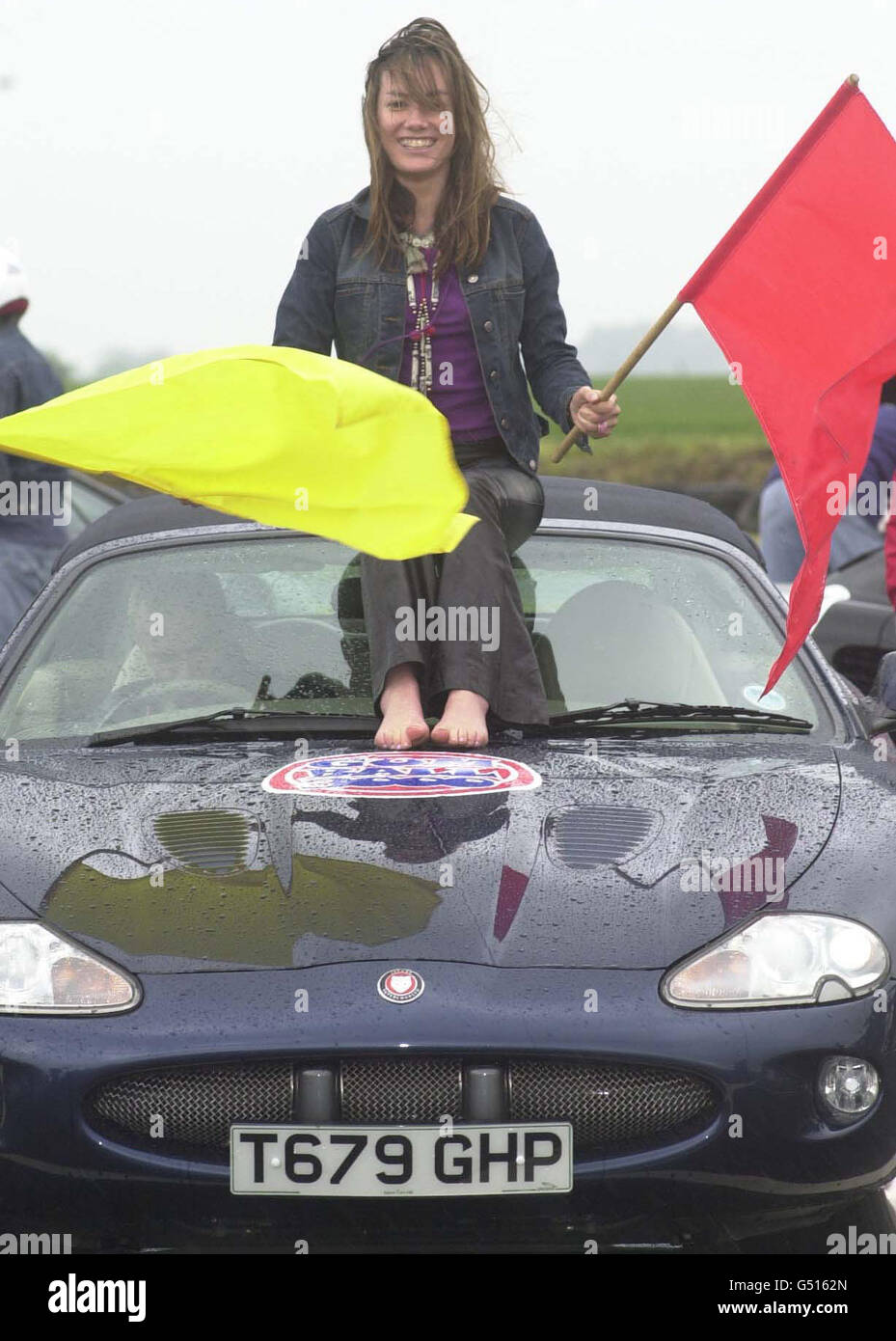 Socialite celebrity Tara Palmer-Tomkinson rides on the roof of a Jaguar XKR car with actor and musician 'Goldie' behind the wheel, at the Gumball 3000 rally at the Lotus Factory in Norfolk. Stock Photo