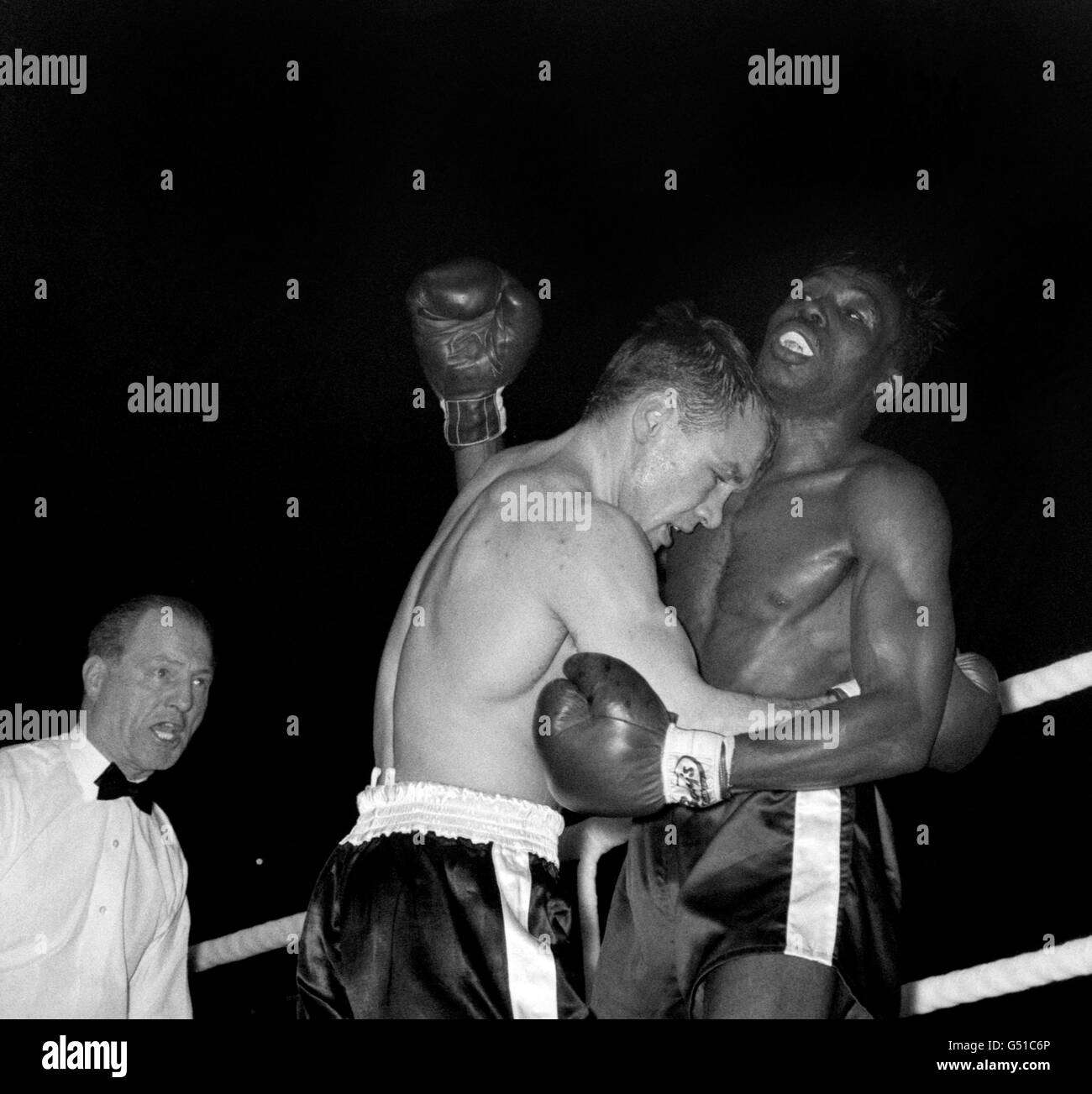 British challenger Dave Charnley (l) pins his American opponent Joe Brown against the ropes, watched by referee Tommy Little, during the their fight. Joe Brown went on to win on points after 15 rounds. The fight was voted 1961 Ring Magazine Fight of the Year. Stock Photo
