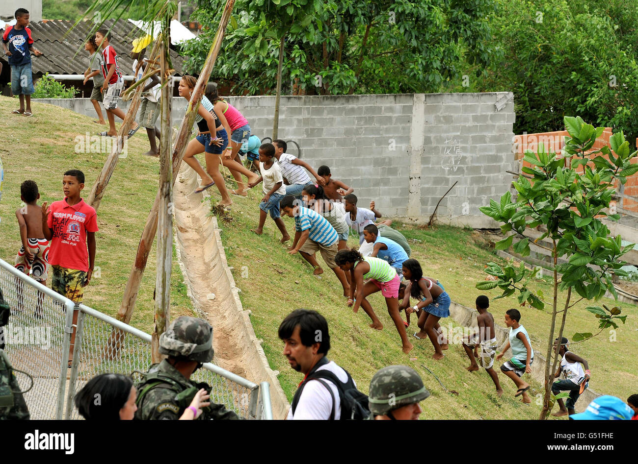 Local children rush up a slope to catch a glimpse of Prince Harry during a visit to the Favella of Complexo do Alemao in the northern suburb of Rio De Janeiro Brazil. Stock Photo