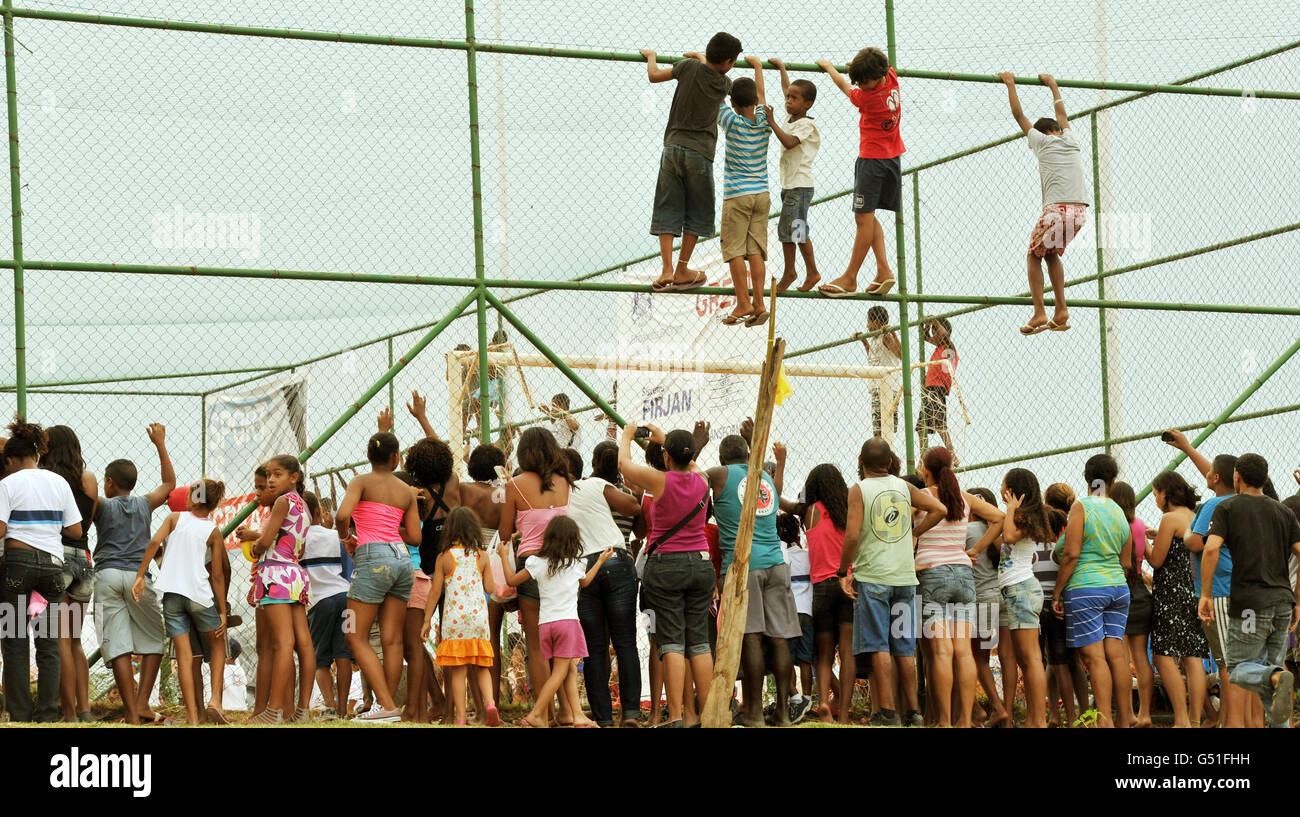 Local children climb a fence to catch a glimpse of Prince Harry during a visit to the Favella of Complexo do Alemao in the northern suburb of Rio De Janeiro Brazil. Stock Photo