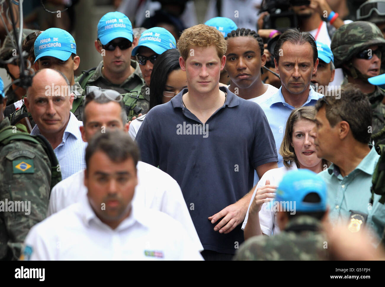 Prince Harry is surrounded by a huge security cordon as he tours the Favella of Complexo do Alemao in the northern suburb of Rio De Janeiro Brazil. Stock Photo