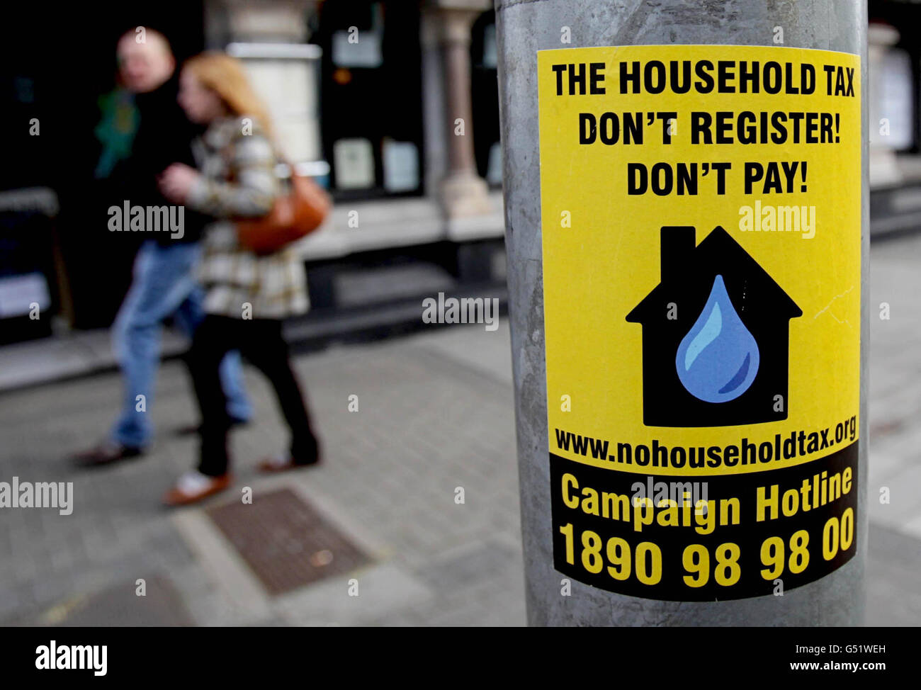 A couple walk past a sticker urging a boycott of the controversial household tax in Dublin. Stock Photo