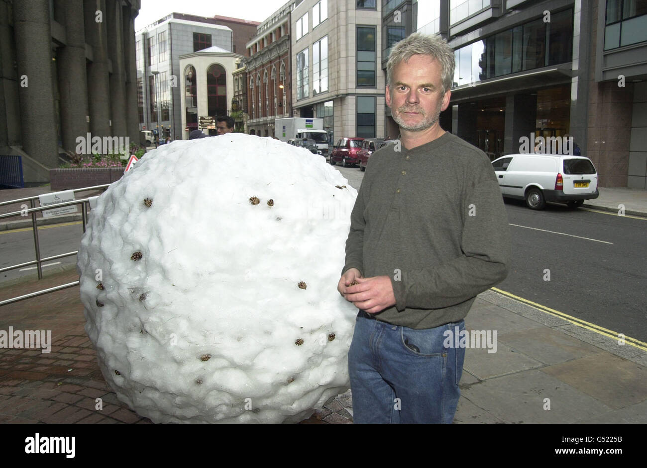 British sculptor Andy Goldsworthy stands in a London street next to a snowball which is forming part of an unusual art exhibition. The thirteen one ton snowballs will melt over a period of three to five days to reveal different materials. * which he packed into them, including sheep's wool, chestnut seeds, elderberries and barbed wire. Stock Photo