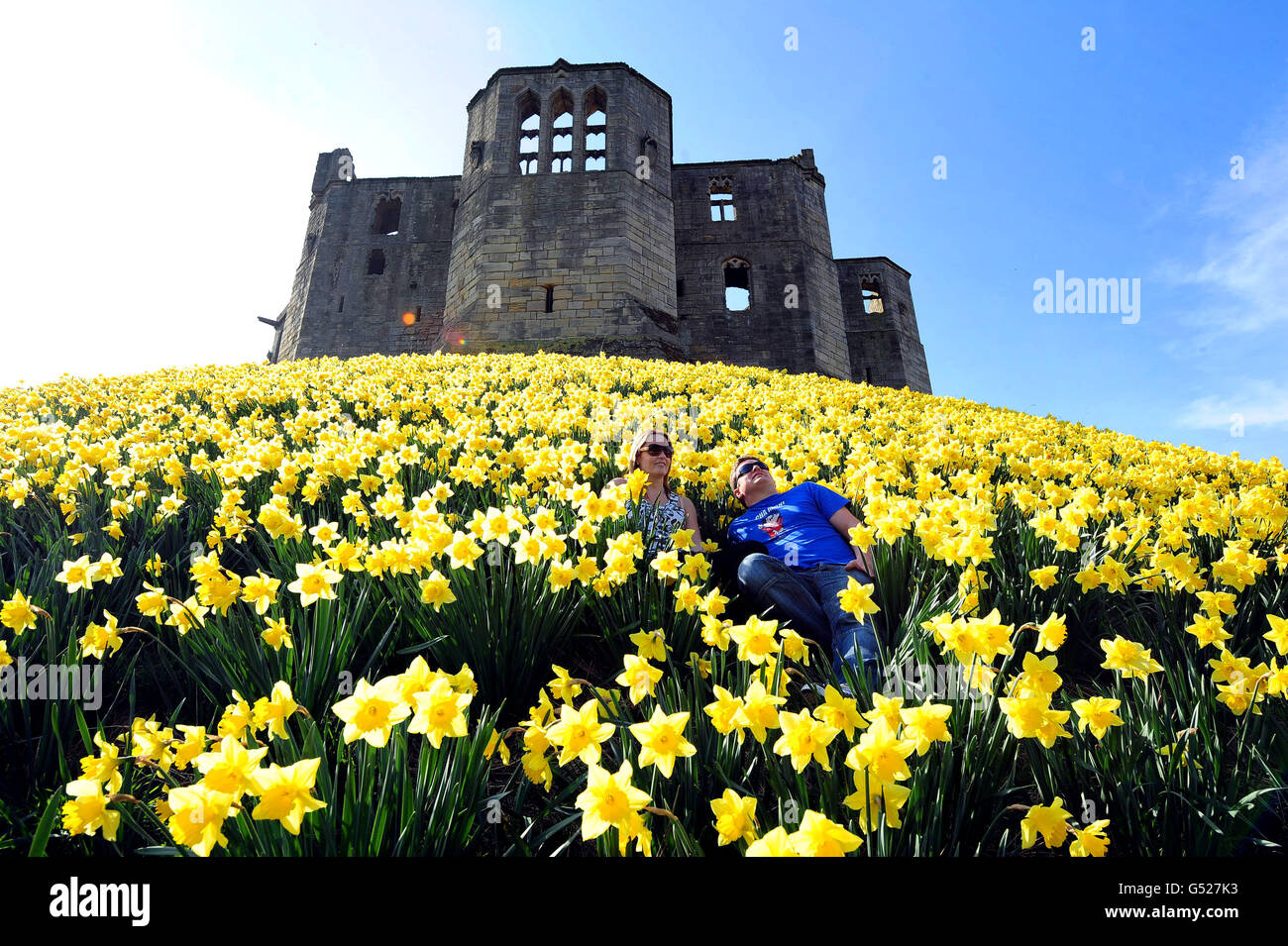 Cherry Lewin, 38, (left) and Tony Johnson, 36, enjoy the warm weather amongst daffodils at Warkworth Hermitage in Northumberland. Stock Photo