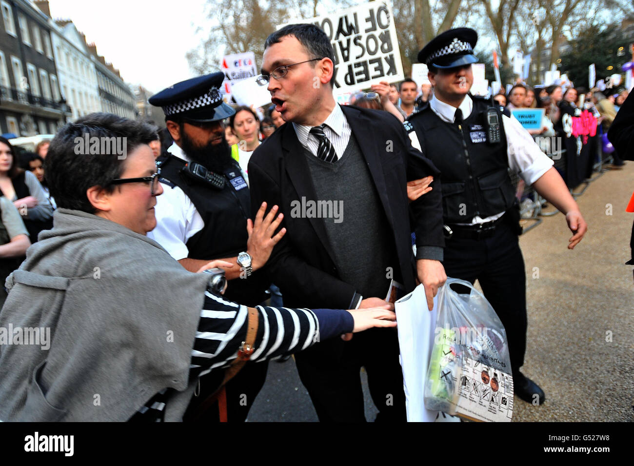 Police intervene as a woman grabs an anti-abortion poster from a man taking part in a anti-abortion vigil in Bedford Square, London. Stock Photo