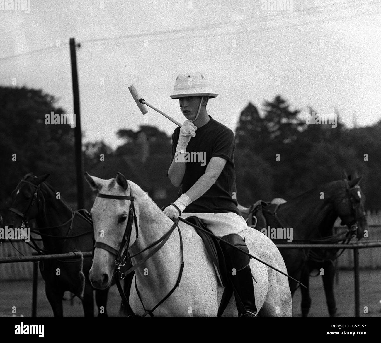 The Prince of Wales adjusts his chinstrap as he goes out to play for Rangers, in a match for the Chairman's Cup against Chiesmans during a Household Brigade Polo Club match, at Windsor Great Park. Stock Photo