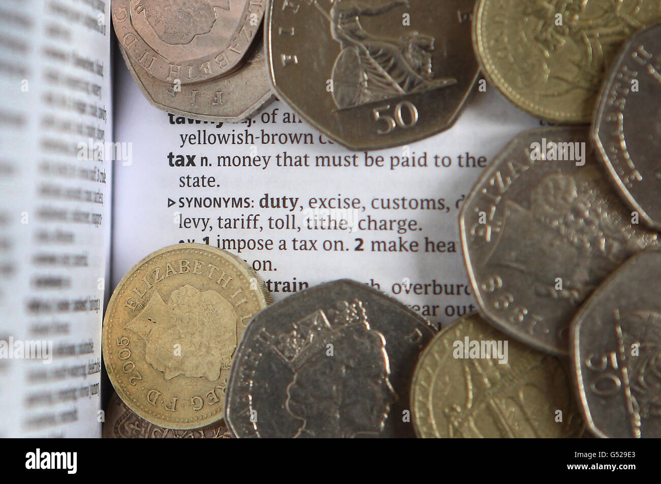 A general view of the dictionary meaning of Tax surrounded by coins, ahead of tomorrow's Budget. Stock Photo