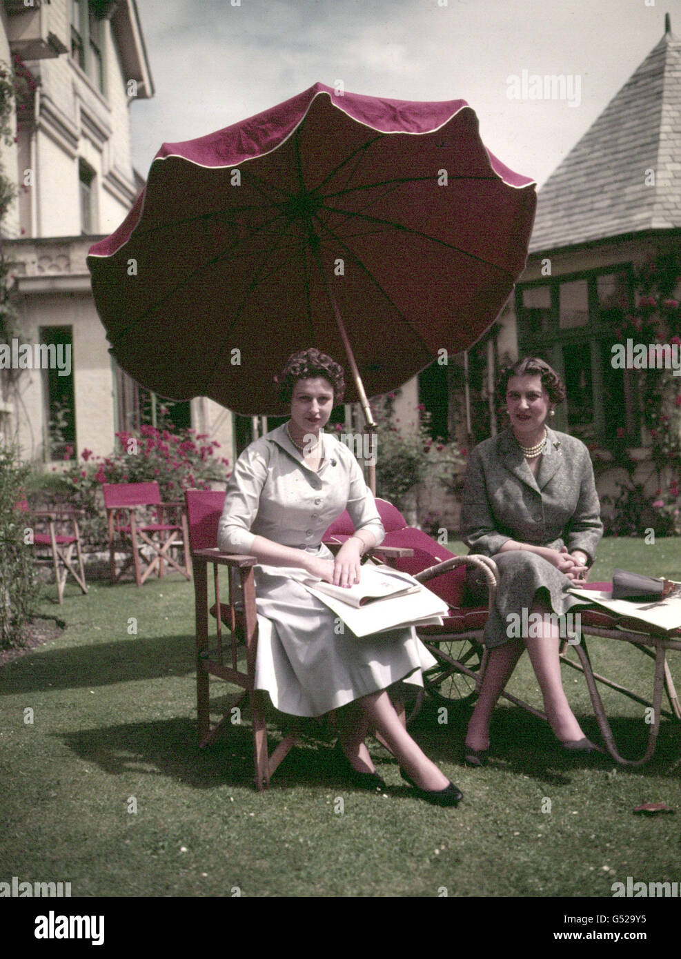 JULY 1954: Princess Alexandra (b.25/12/36) and her mother, Princess Marina of Kent (right), seated underneath an umbrella. Stock Photo