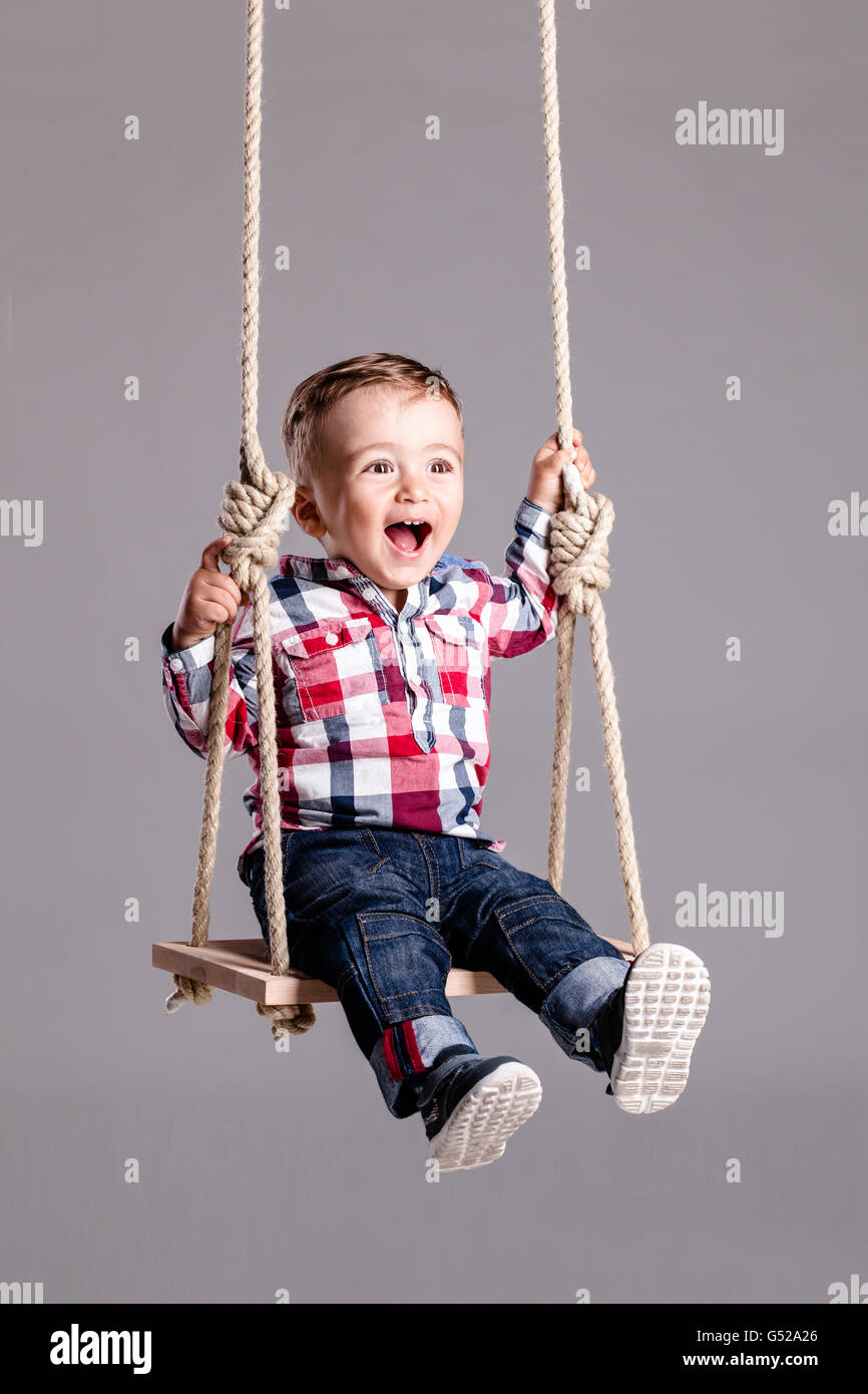 happy little boy swinging on a wooden swing Stock Photo Alamy