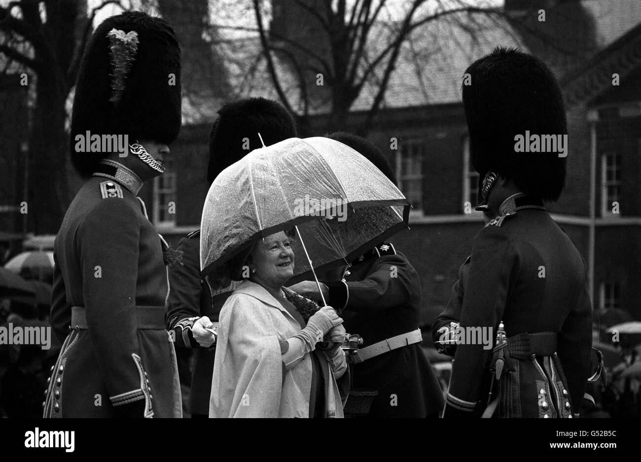 QUEEN MOTHER ON ST. PATRICK'S DAY 1980: An ample amount of shamrock adorns the Queen Mother's rain cape at Victoria barracks, Windsor, where she presented officers and men of the Irish Guards with shamrock during their traditional St. Patrick's Day parade. Stock Photo