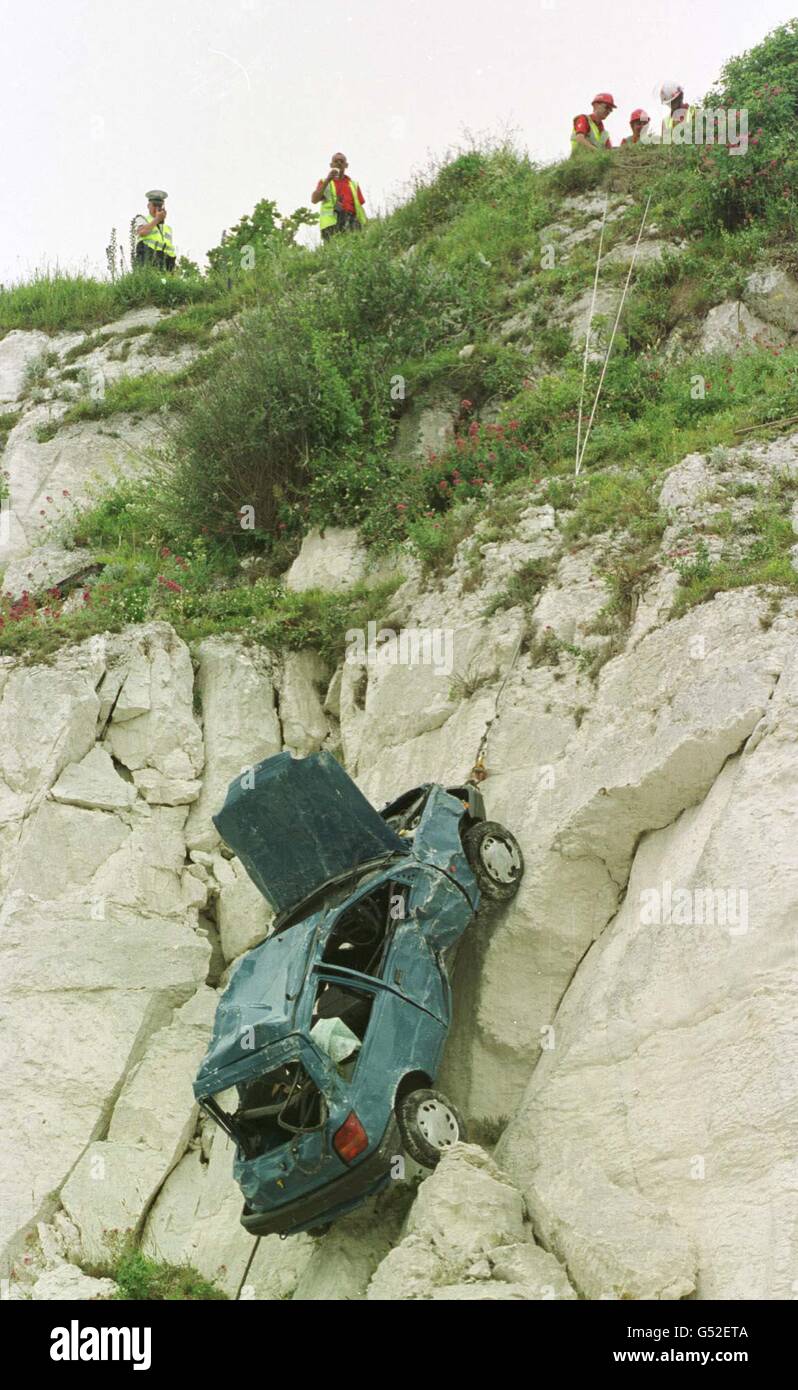 Police crash investigators watch as the blue Ford Fiesta which was involved in a serious accident is winched up the 150ft cliff face which it plunged over on 27/06/00. The driver of the car, Peter King, aged 17, of Eastbourne, suffered severe head injuries. * ...two of the injured were named as Kelley Anne-Philips (correct), 17 and Katie Thompsett, 17, both of Eastbourne. The car lost control and fell over the chalk cliff, a beauty spot at Hollywell, Eastbourne, known locally as the Sugar Loaf. Stock Photo