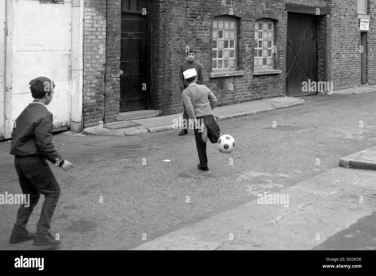 Youngsters between the age of nine and 14 play football outside the Bermondsey factory of F.M. Langford Limited, Manufacturing Chemist of Maltby Street. The children turned up to work at the factory this morning but were turned away by the factory's manager when he heard of a row that had broken over allegations that the factory employed 'child labour'. Nevertheless the children hung around hoping that they might be given jobs later at the firm. The Inner London Education Authority (ILEA) were investigating claims that children had been employed at the factory. The Authority heard about the Stock Photo