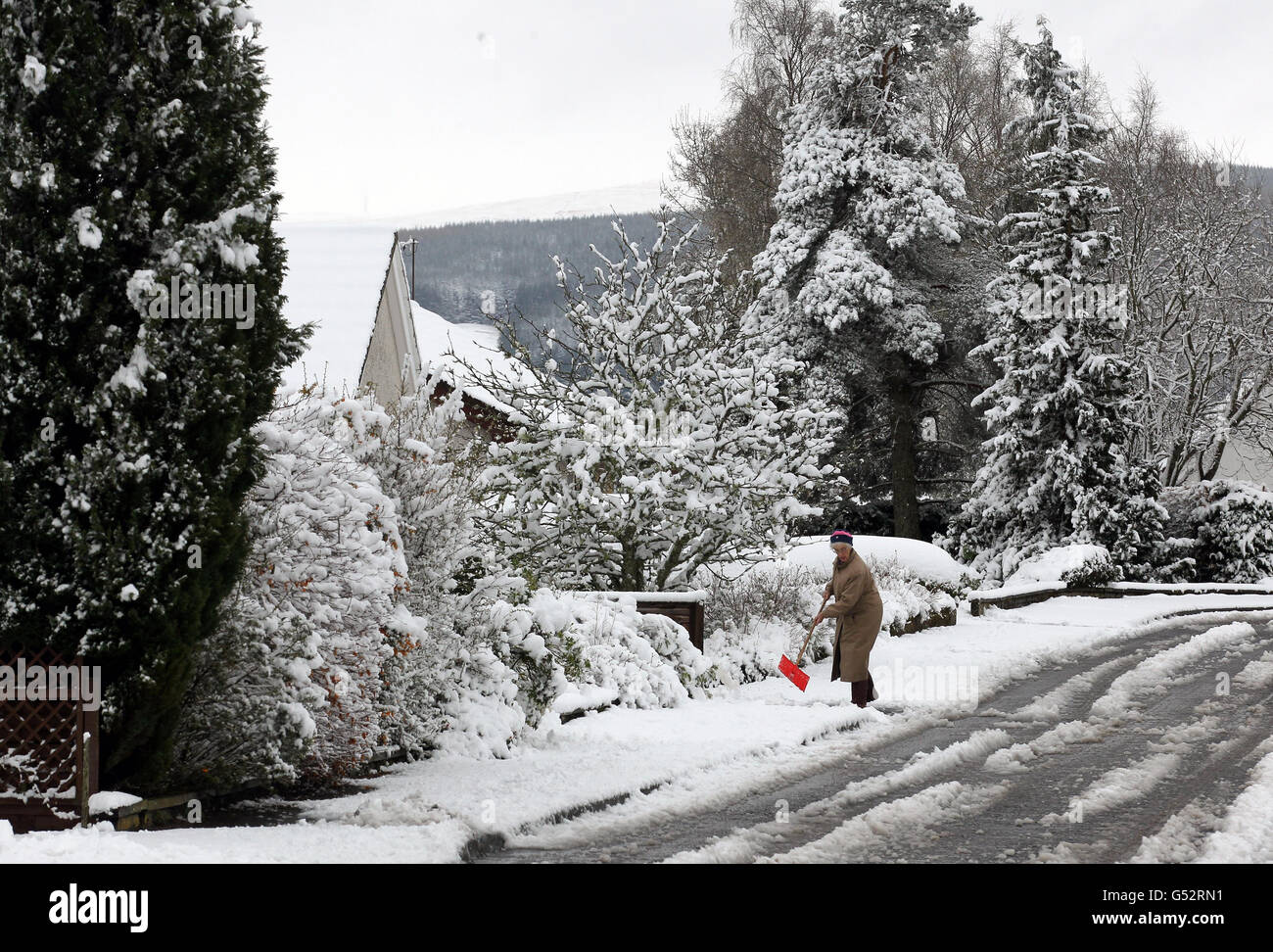 A woman clears her paths in her street at Auchterarder as more than six