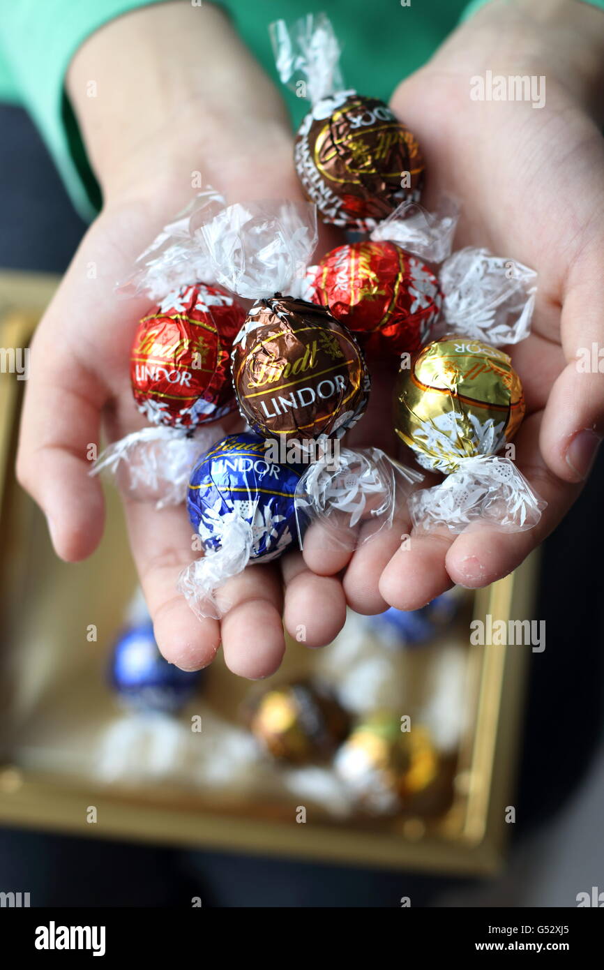 Close up of hand holding Assorted Lindt Lindor Chocolates in metallic