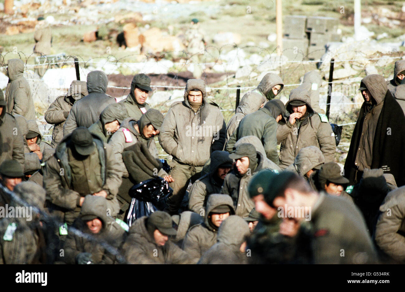 THE FALKLANDS WAR : Argentine prisoners of war, captured during the establishment of a bridgehead at San Carlos Water, are guarded by Royal Marines (foreground) in a barbed wire compound. The bridgehead was established on May 21st by British Falkland Islands Task Force troops. Stock Photo
