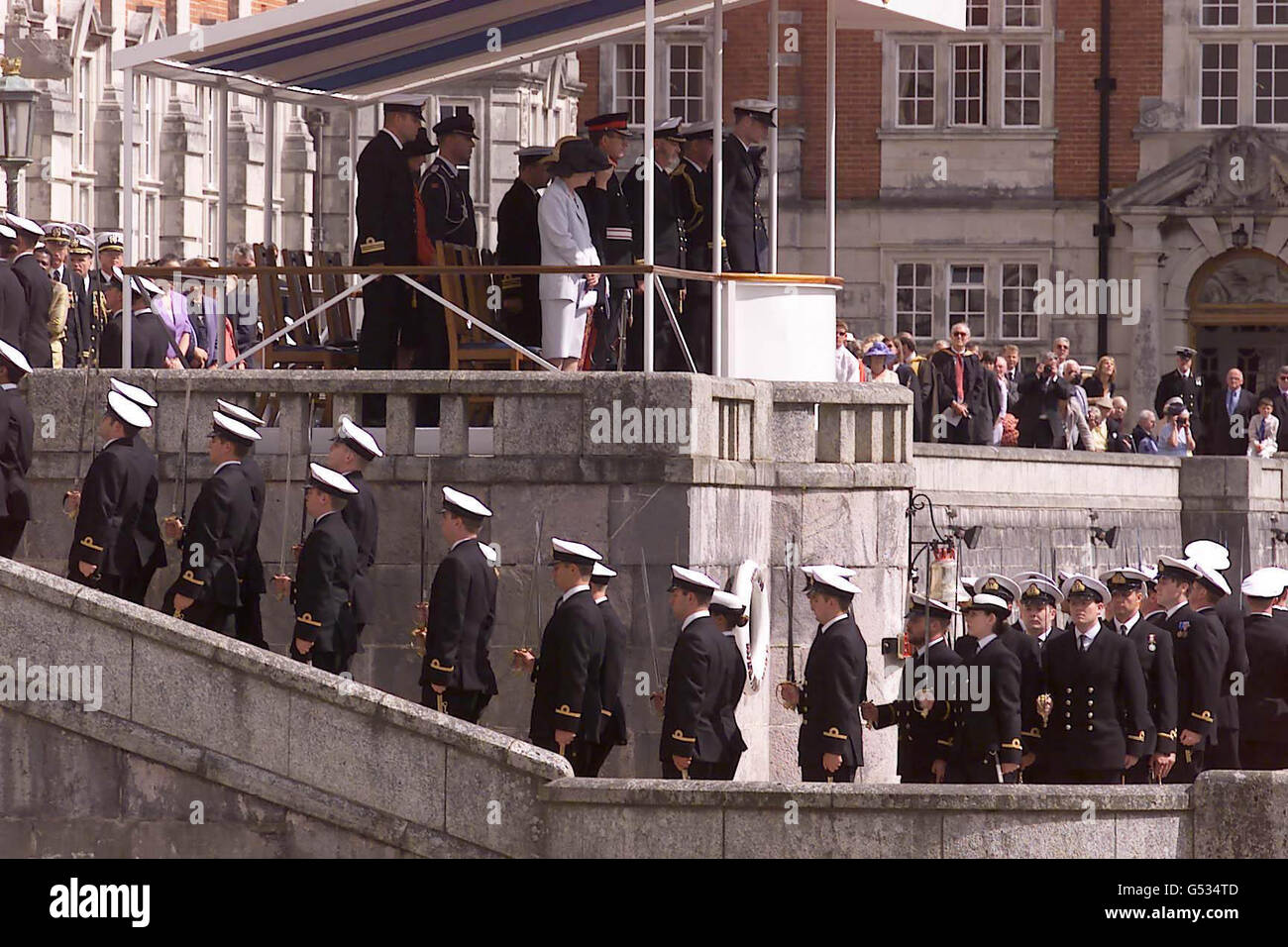 His Royal Highness Crown Prince Haakon of Norway (at front of podium) takes the salute at the Britannia Royal Navy College in Dartmouth, Devon. Known as the Lord High Admiral's Divisions, it marks the passing out of officers before being assigned to their ships. * Normally Her Majesty the Queen of England or a member of the British royal family attends the event, but this year they have been kept away by the 100th birthday celebrations of the Queen Mother. Stock Photo